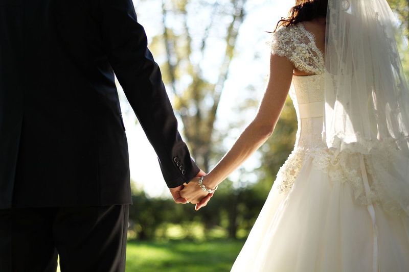 Eine Braut und ein Bräutigam halten sich an den Händen. | Quelle: Shutterstock