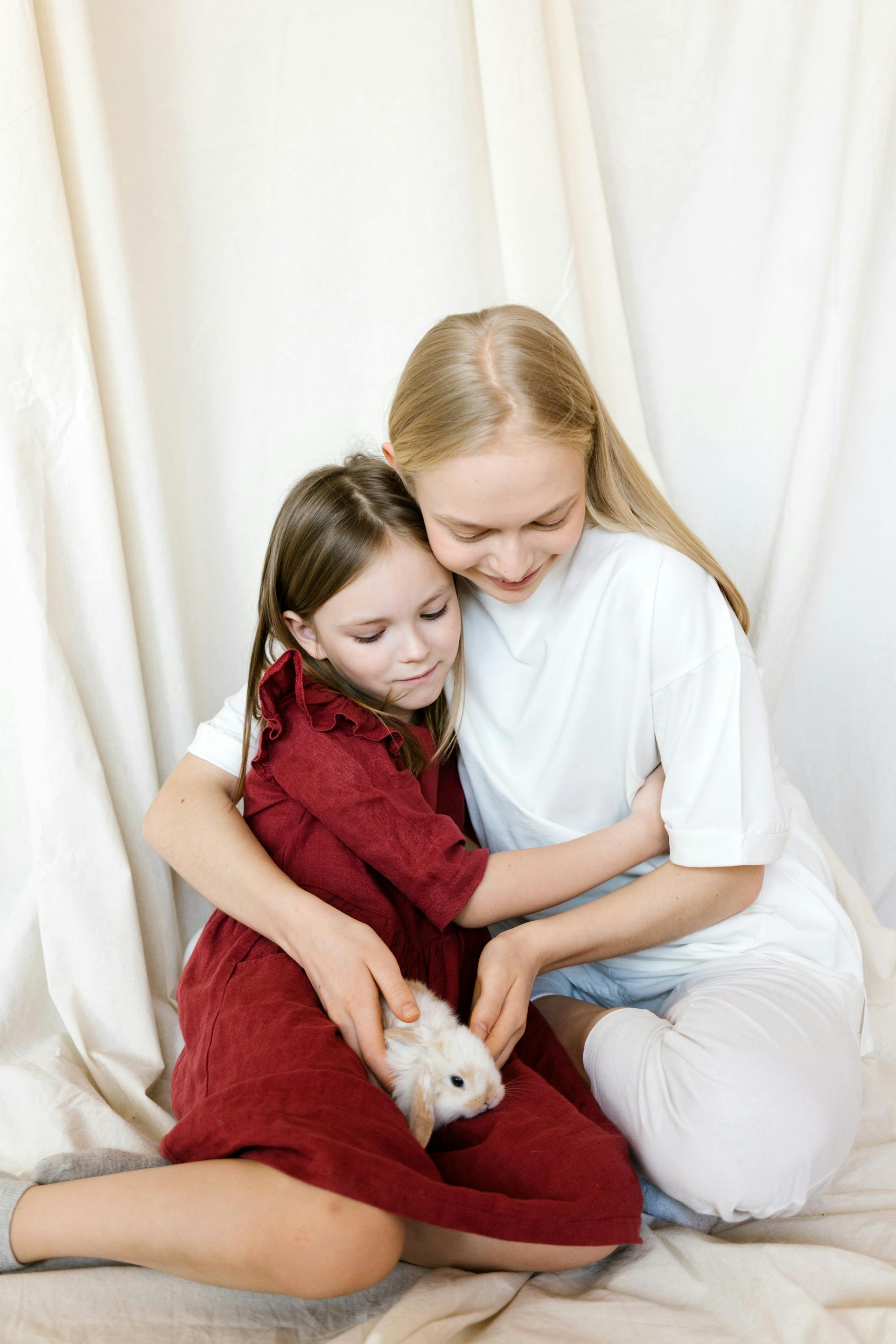 Ein junges Mädchen, das seine Mutter umarmt, während es sich ein Kaninchen ansieht | Quelle: Pexels