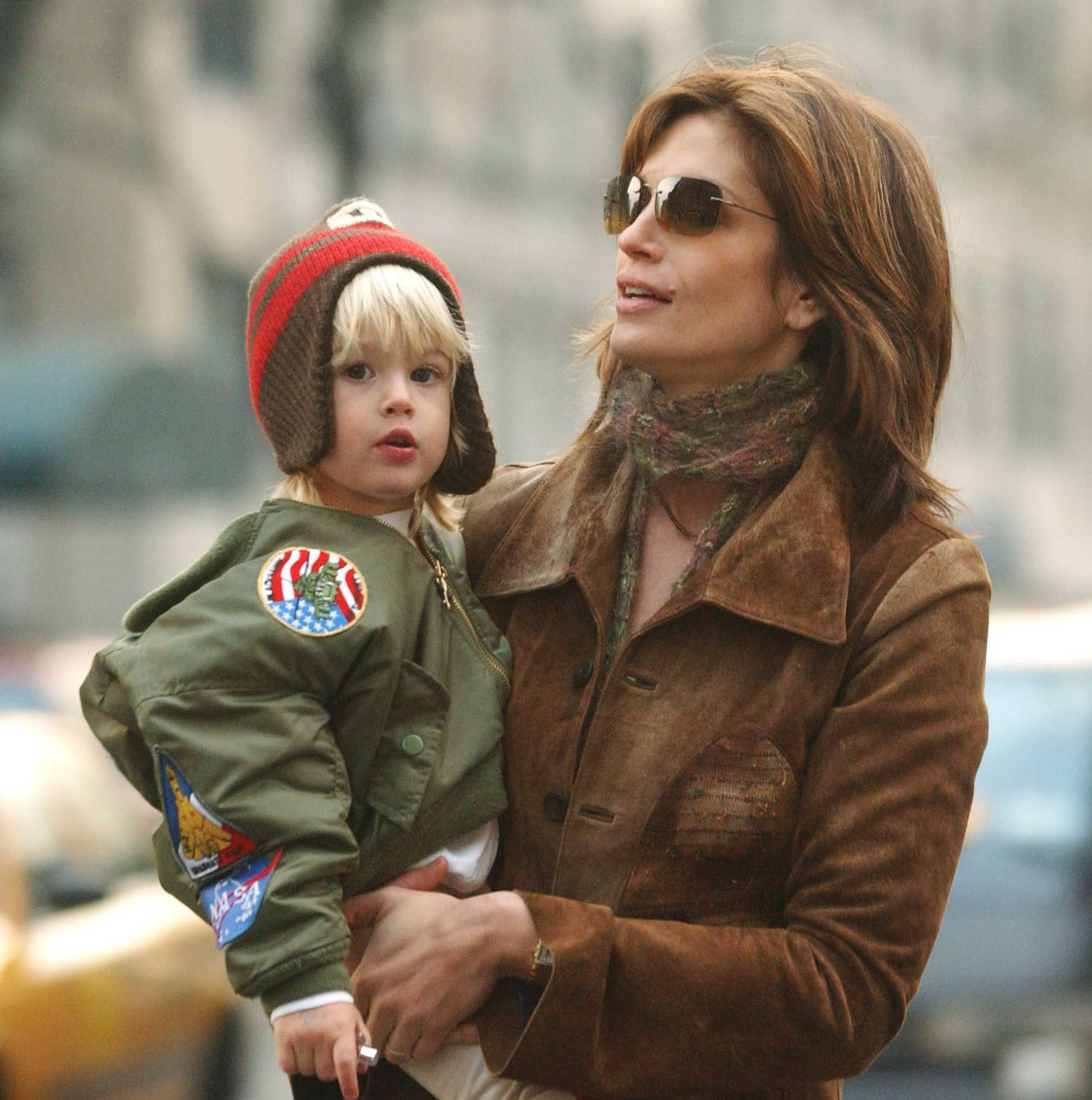 Cindy Crawford hält den mit großen Augen staunenden Presley Gerber bei einem Spaziergang durch New York City am 8. März 2002 im Arm. Gekleidet in eine Jacke im Pilotenstil, verziert mit Aufnähern zum Thema Weltraum, und eine Strickmütze mit Ohrenklappen, sticht Presley mit seinem goldenen Haar und seinem engelsgleichen Gesicht hervor – ein erster Vorgeschmack auf die fotogenen Gesichtszüge, die ihm später einen Platz in Modekampagnen sichern sollten.