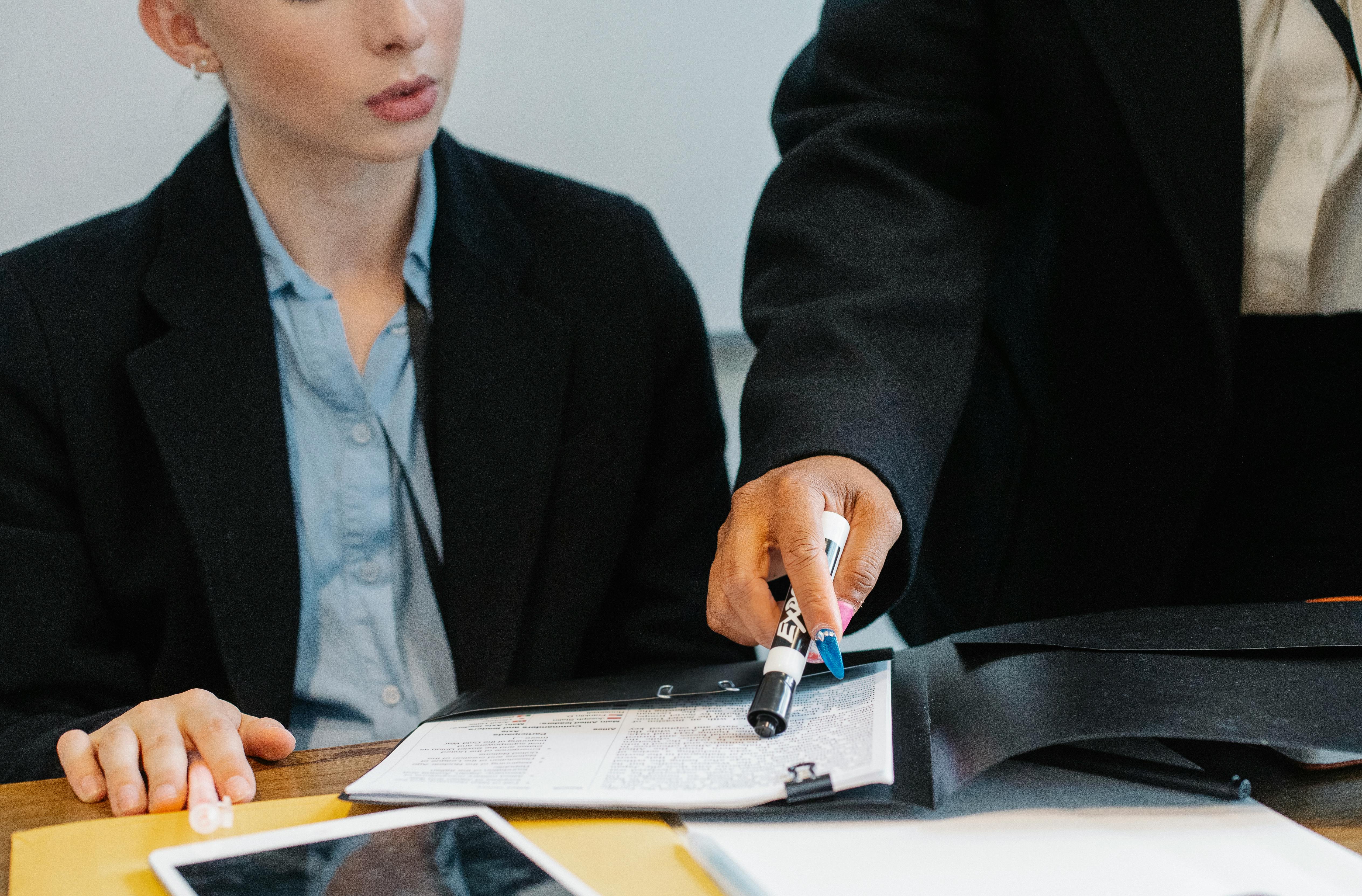 Zwei Frauen diskutieren über Papierkram | Quelle: Pexels