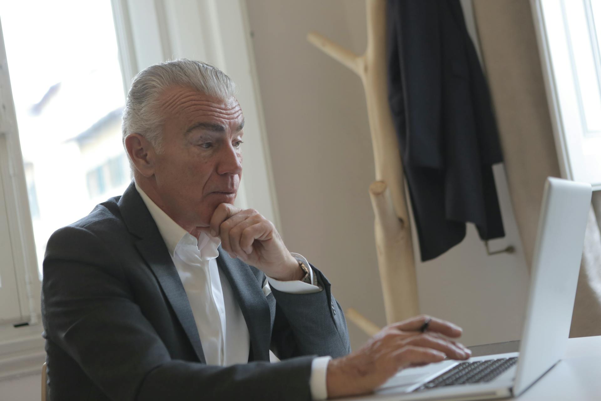 Ein eleganter älterer Mann benutzt seinen Laptop in seinem Büro | Quelle: Pexels