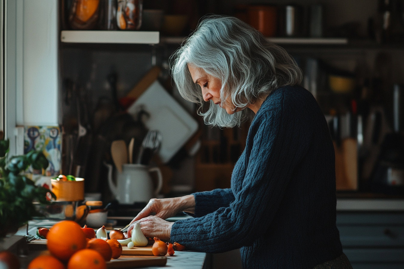 Mulher na casa dos 50 anos na cozinha, concentrada em cortar ingredientes | Fonte: Midjourney