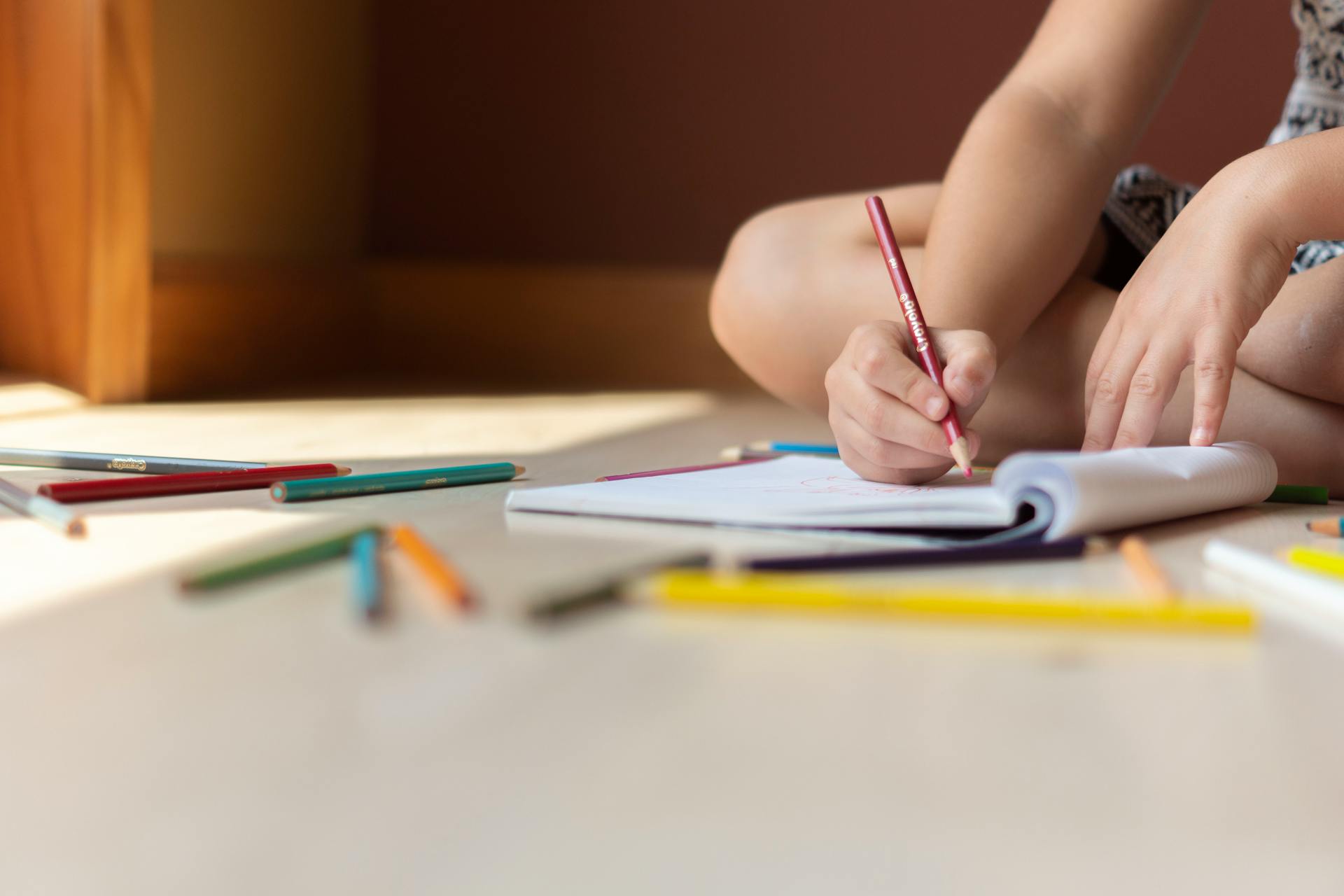 Ein Kind sitzt auf dem Boden und zeichnet | Quelle: Pexels