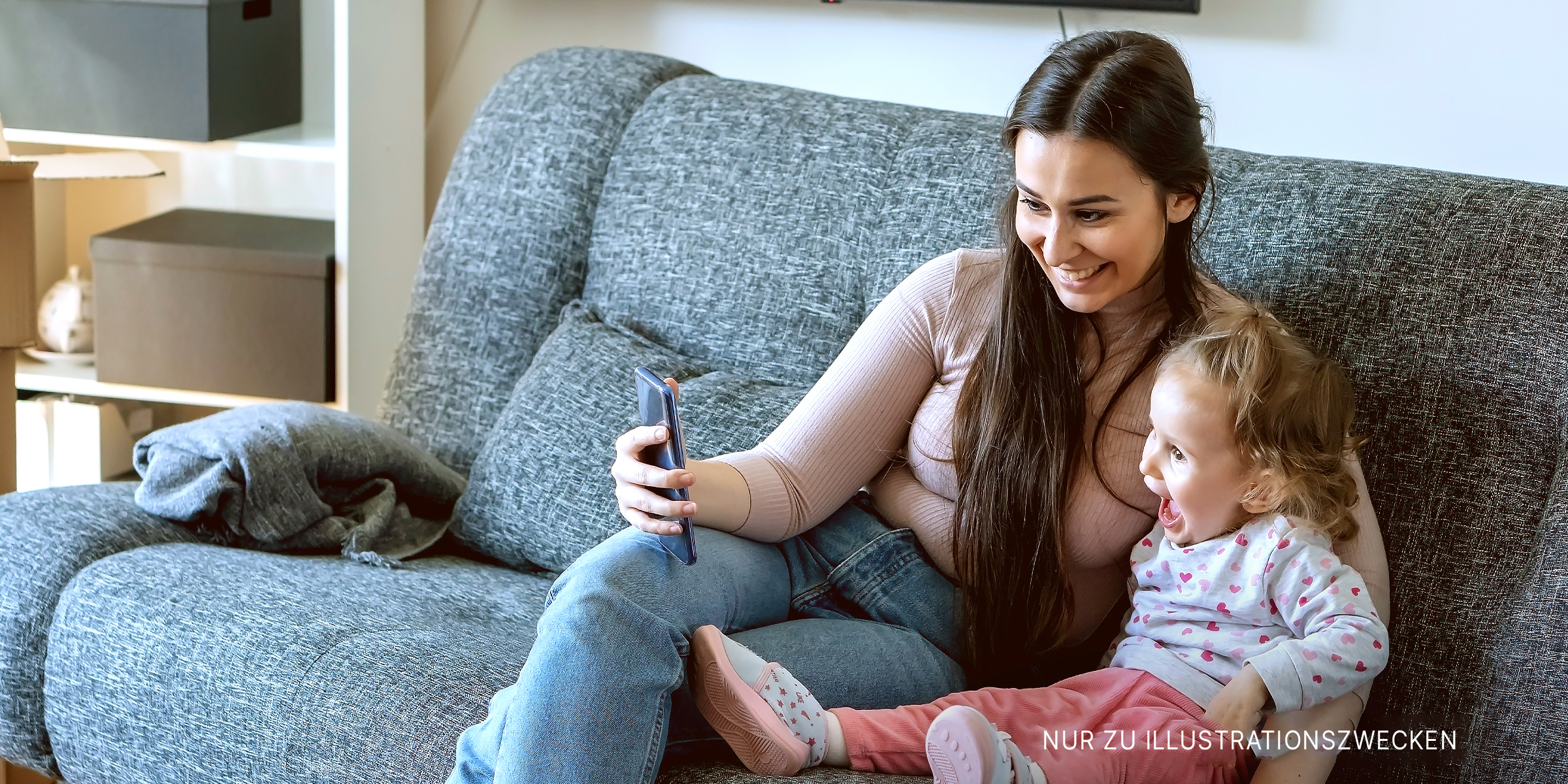 Eine Frau schaut sich ein Handy mit ihrem Kind an | Quelle: Shutterstock