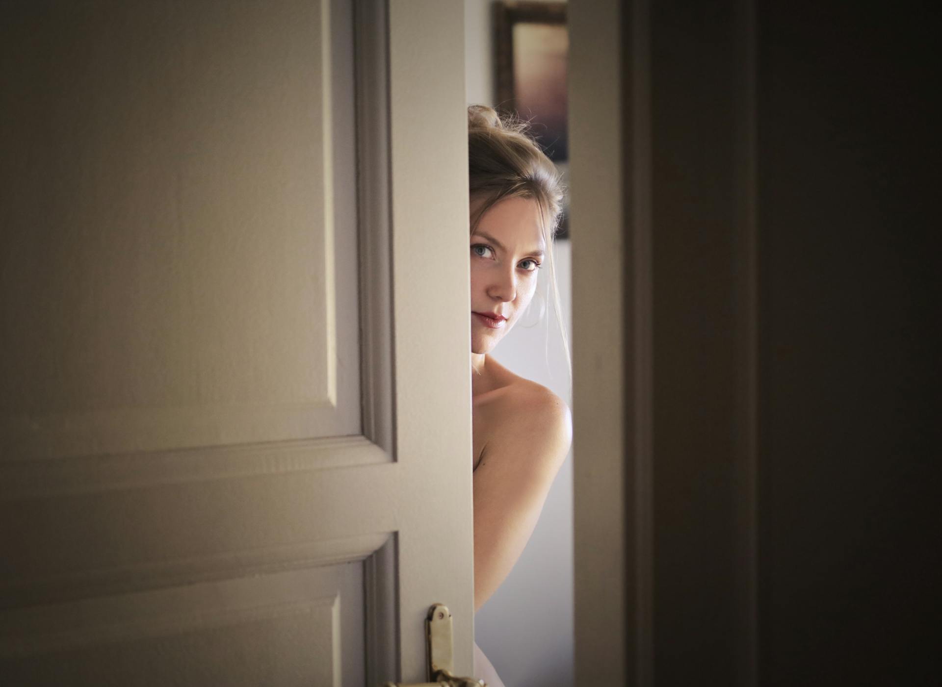 Eine Frau späht um eine Tür herum | Quelle: Pexels