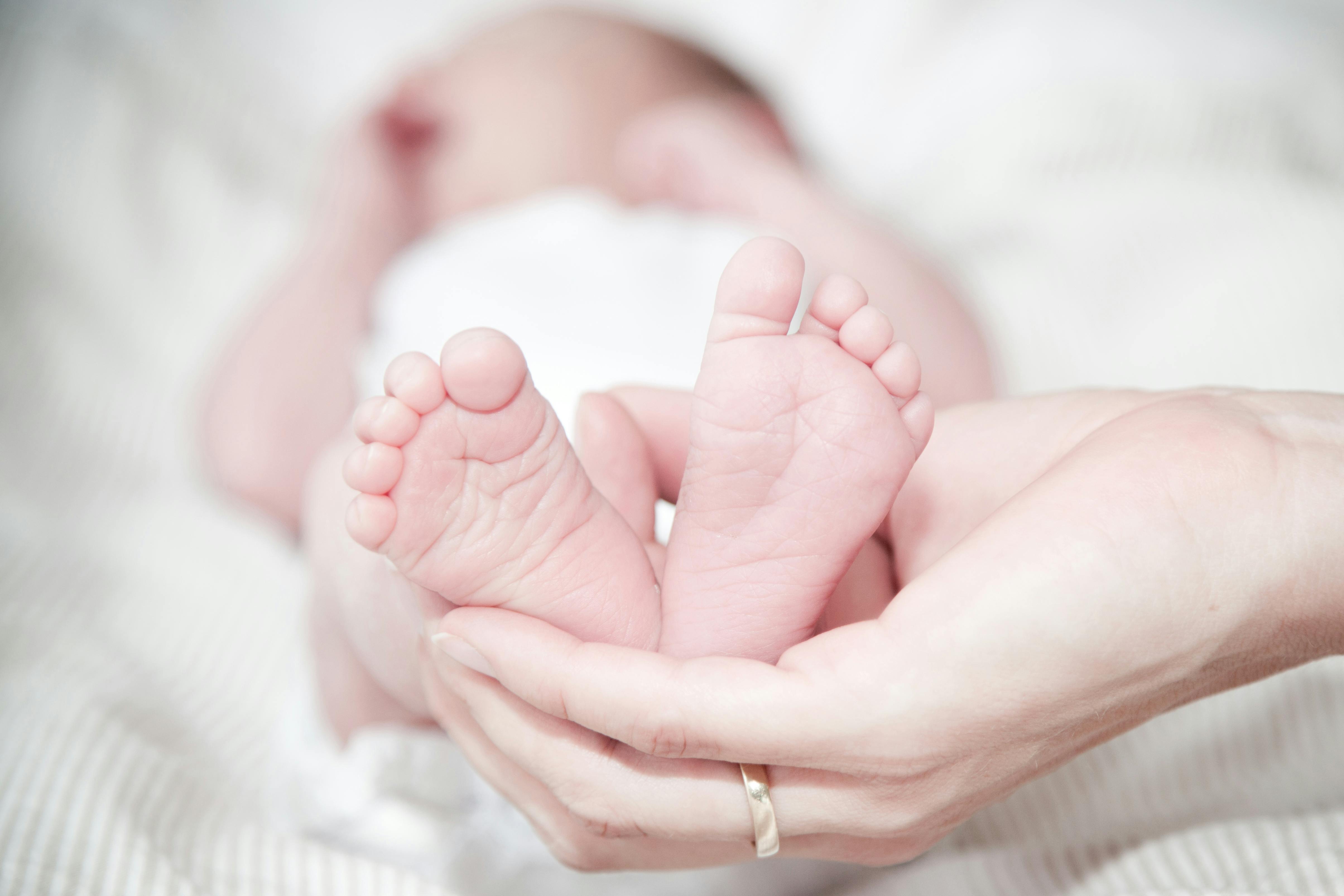 Eine Frau, die die Füße ihres neugeborenen Babys hält | Quelle: Pexels
