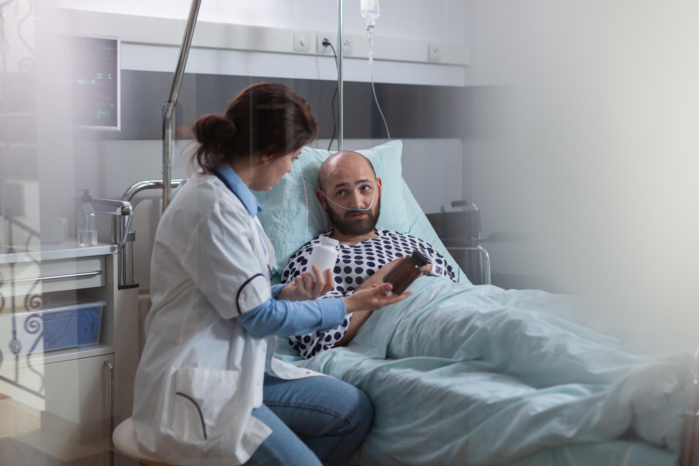 Ein kranker Mann mit einer Nasensauerstoffsonde, der während einer medizinischen Untersuchung im Bett liegt | Quelle: Magnific