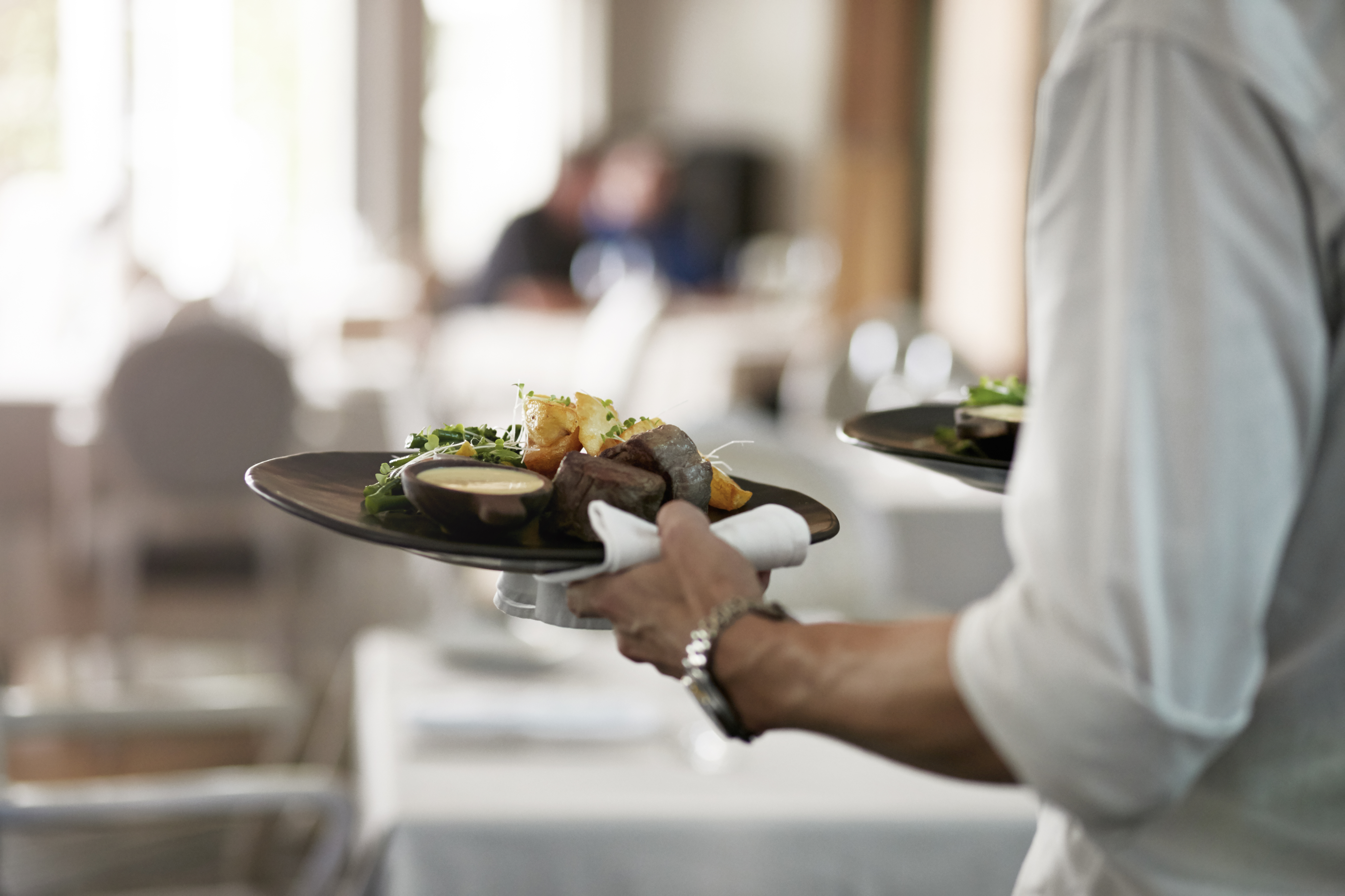 Kellner, der mit Essen gefüllte Teller trägt | Quelle: Getty Images