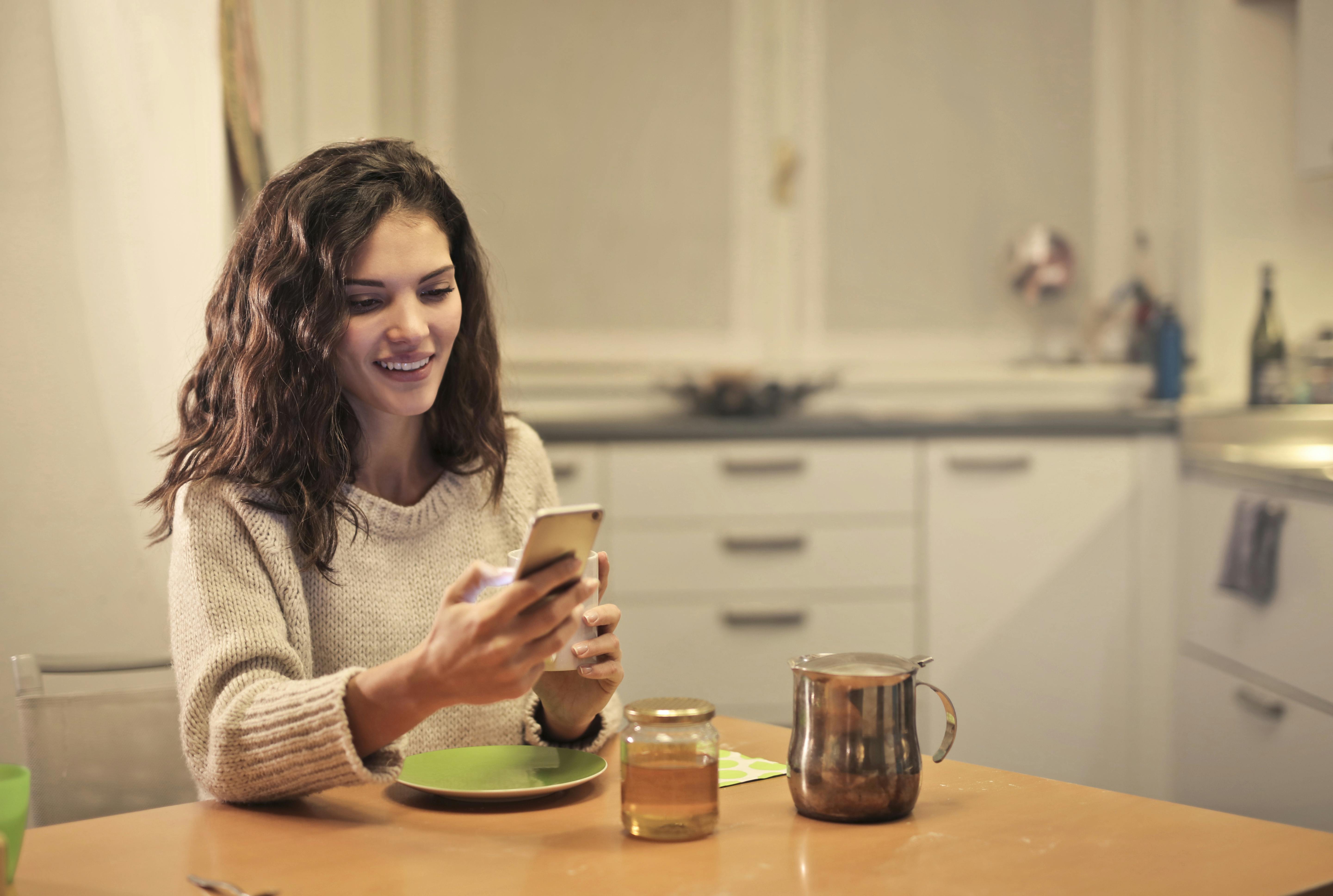 Eine glückliche Frau schaut auf ihr Telefon | Quelle: Pexels