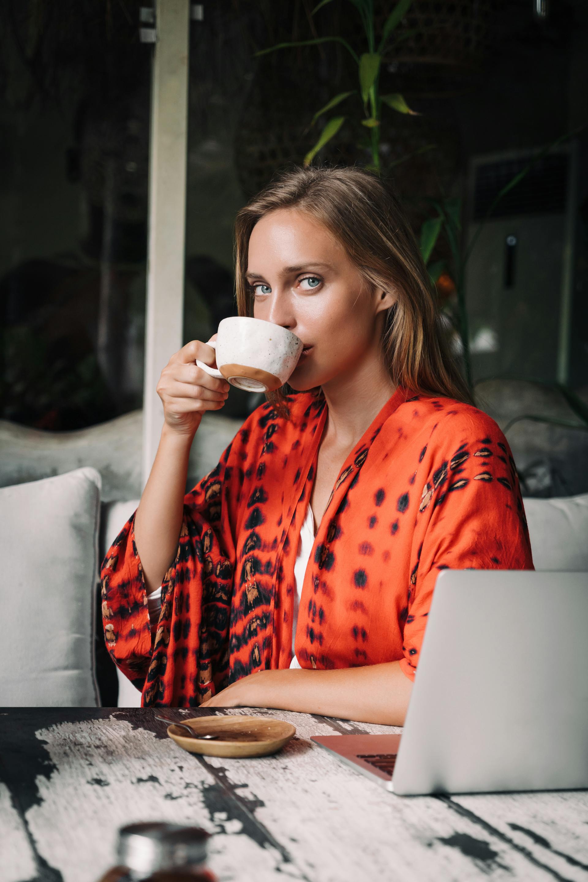 Eine Frau trinkt Kaffee mit ihrem Laptop vor sich | Quelle: Pexels