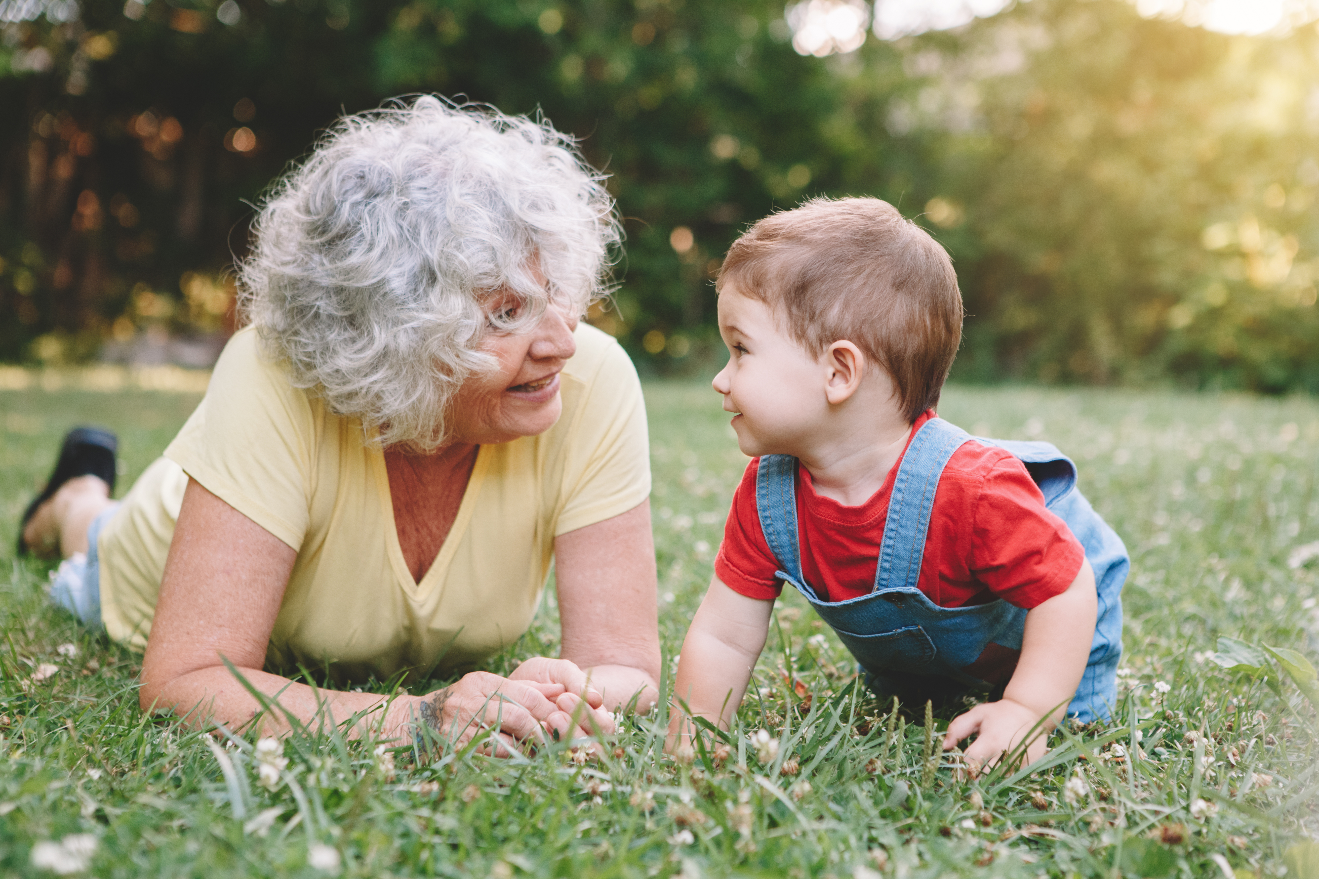 Eine Großmutter und ein Enkelkind liegen im Gras | Quelle: Shutterstock