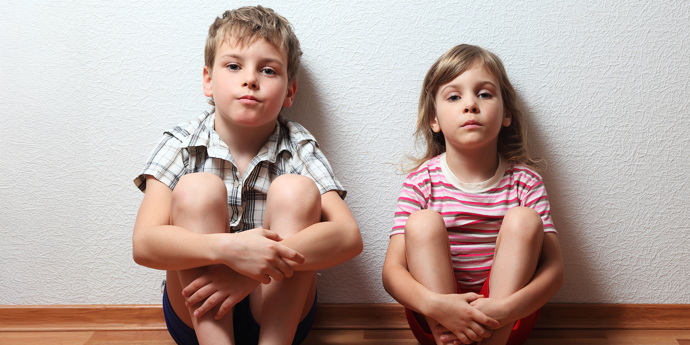 Ein kleiner Junge und ein Mädchen sitzen auf dem Boden | Quelle: Shutterstock