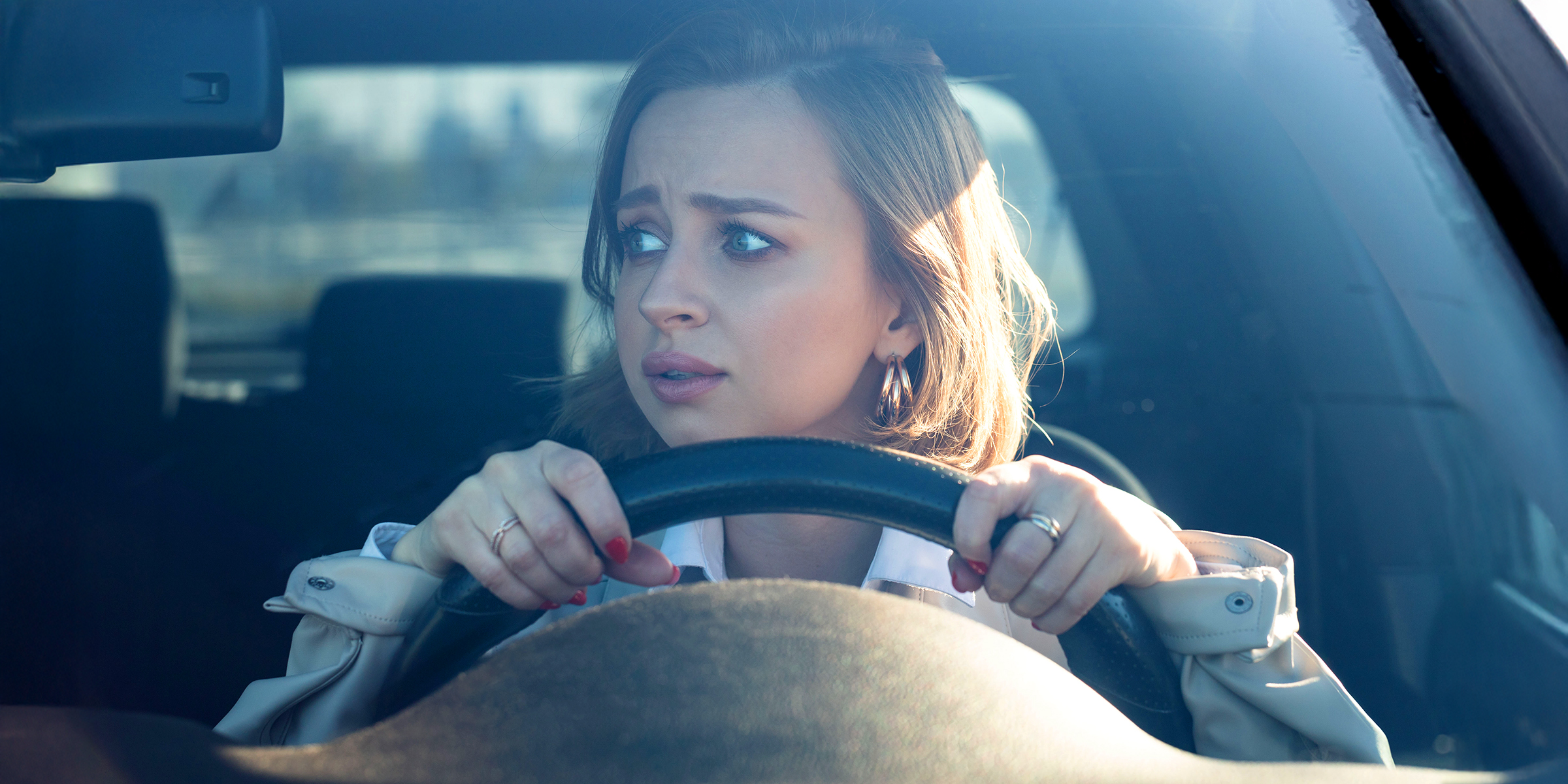 Eine junge Frau, die das Lenkrad umklammert und mit großen, ängstlichen Augen nach vorne starrt | Quelle: Shutterstock