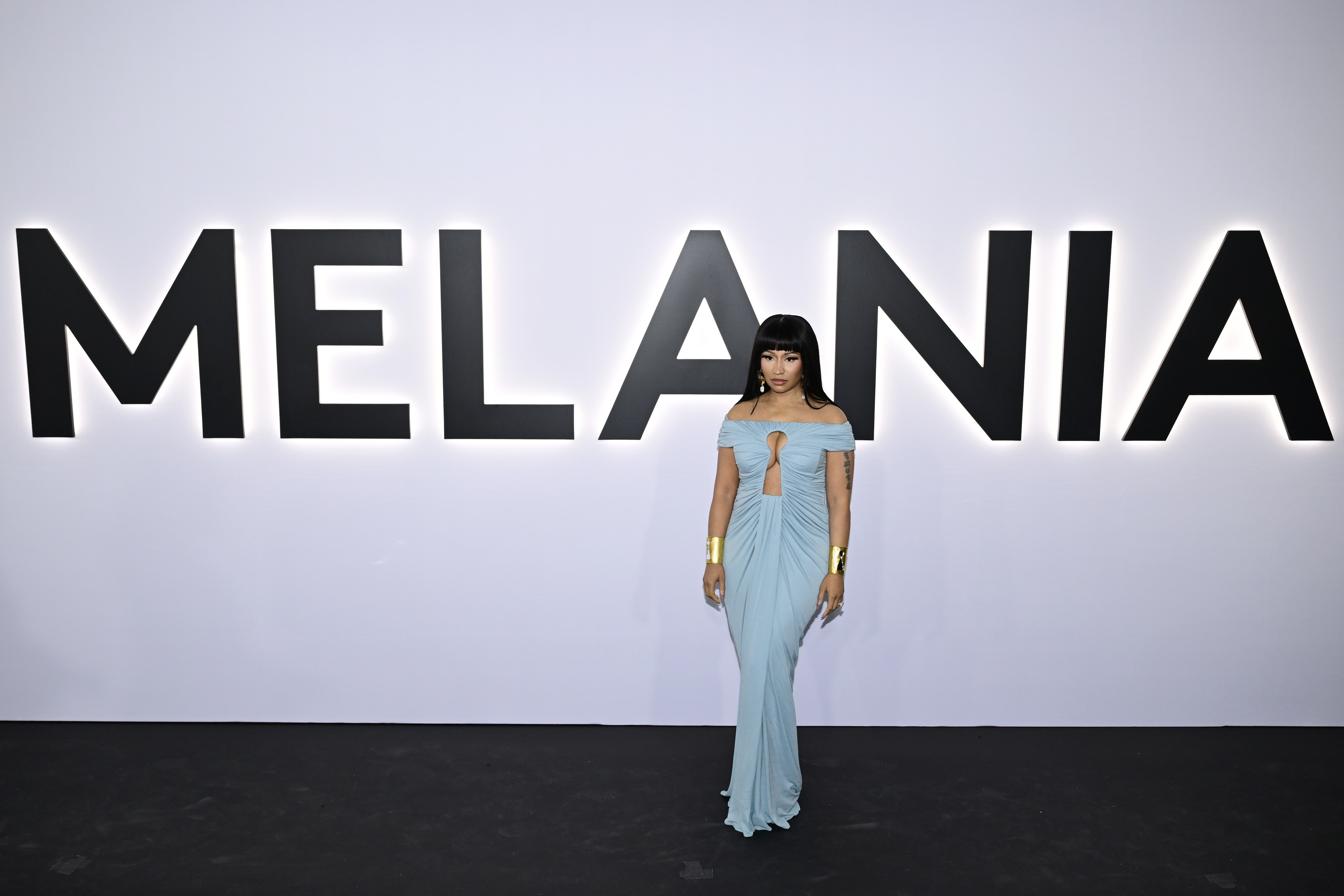 Nicki Minaj posiert bei der Premiere des Dokumentarfilms vor dem riesigen „MELANIA“-Schild und trägt dabei ein hellblaues, schulterfreies Abendkleid mit goldenen Manschetten – eine auffällige Erinnerung an ihre öffentliche Verbindung zur First Lady, noch bevor die neuesten Witze über Donald Trump aufkamen. | Quelle: Getty Images