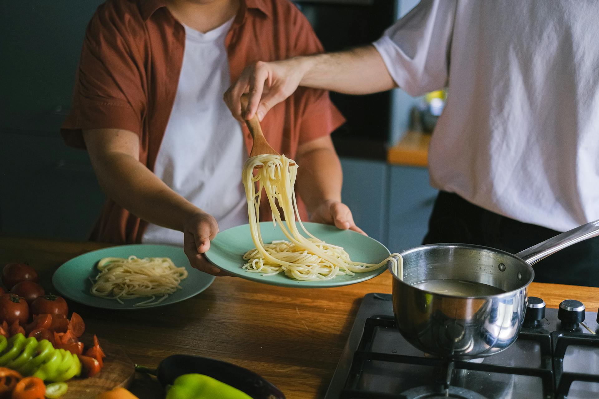 Ein Mann, der gekochte Spaghetti aus einer Pfanne nimmt | Quelle: Pexels