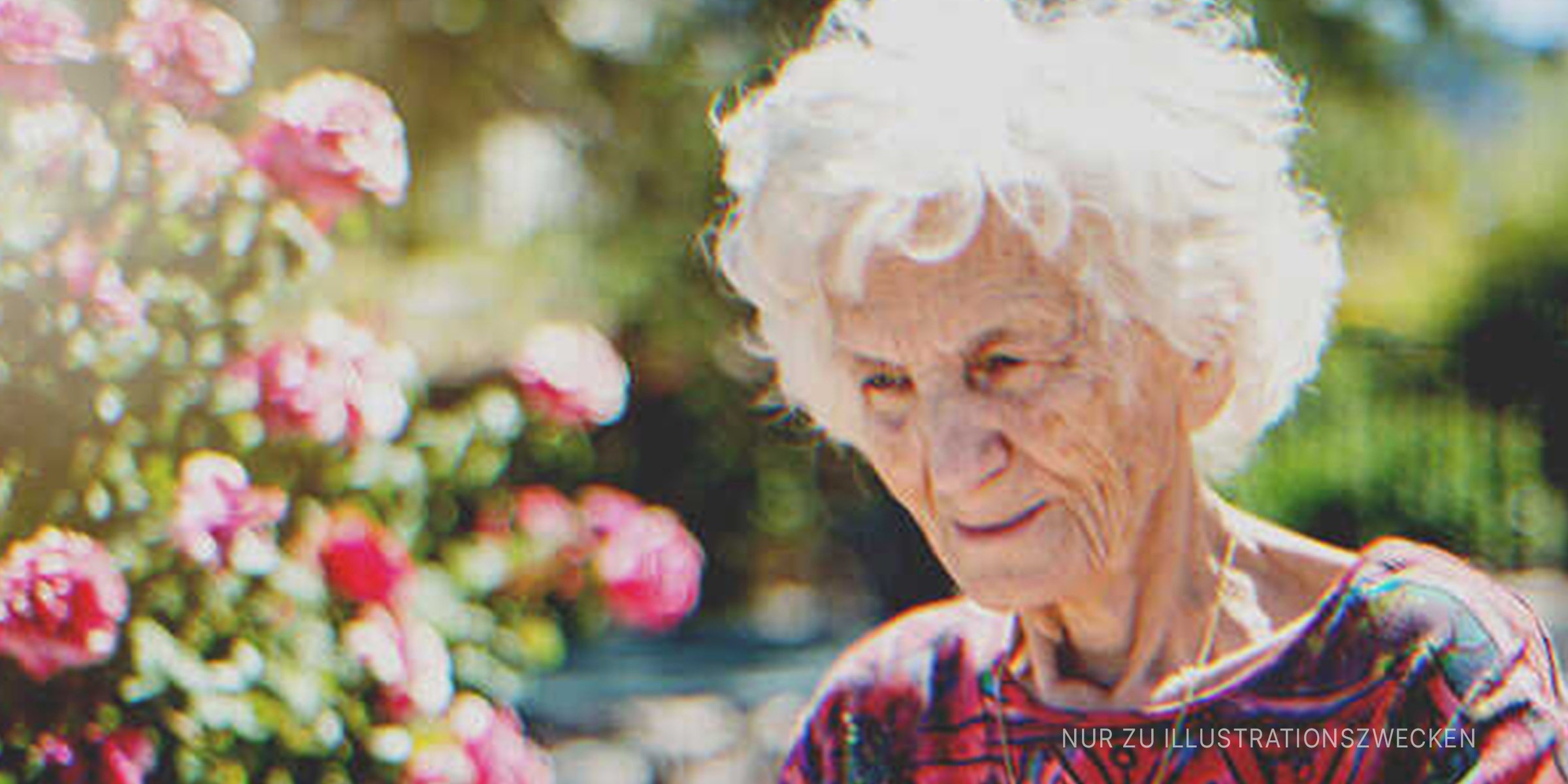 Eine alte Frau, die neben Blumen lächelt. | Quelle: Getty Images