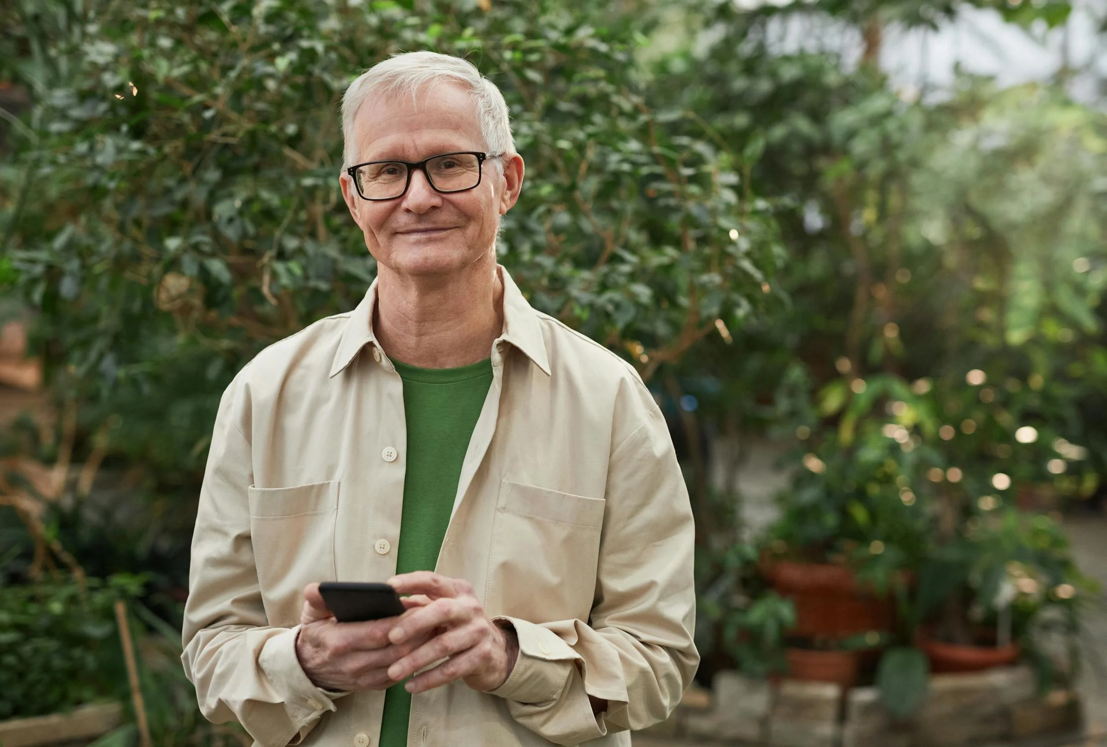 Um homem sorridente segurando seu telefone ⏐ Fonte: Pexels