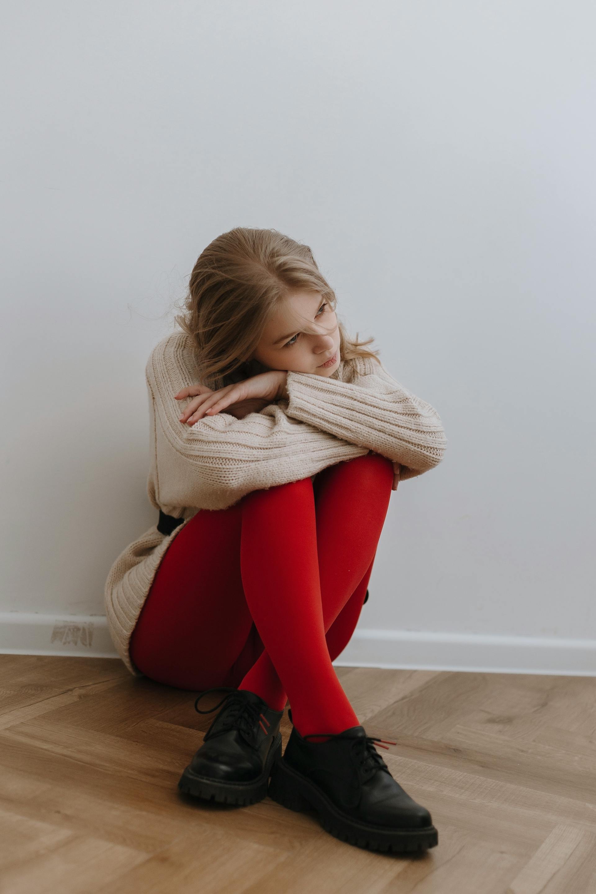 Eine müde Frau, die auf dem Boden neben einer Wand sitzt | Quelle: Pexels