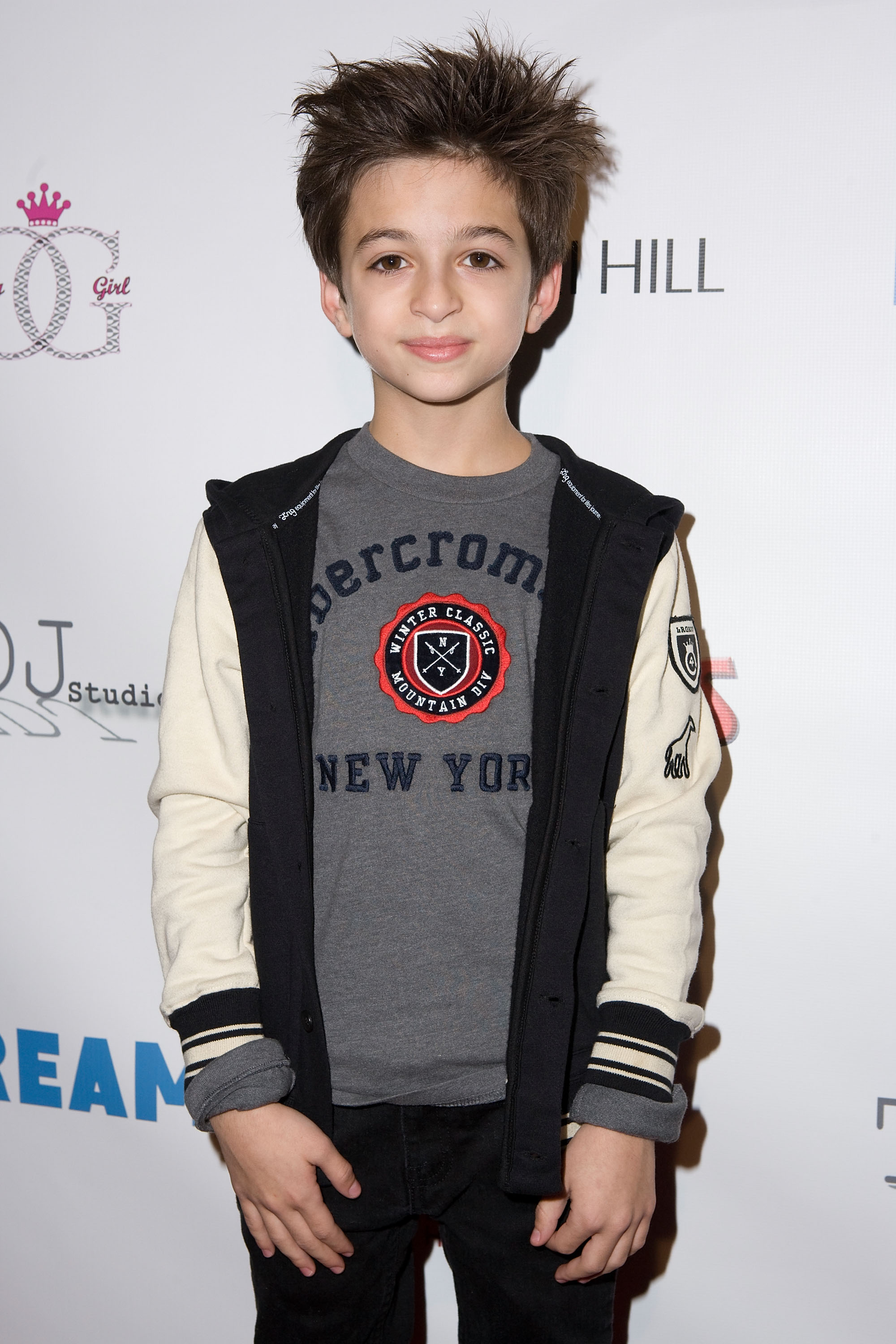 Der junge Künstler nimmt an der 2. jährlichen „Dream Magazine Winter Wonderland Party“ in Los Angeles, Kalifornien, teil und trägt ein graues T-Shirt mit Aufdruck, eine schwarz-cremefarbene Jacke und eine schwarze Hose. | Quelle: Getty Images