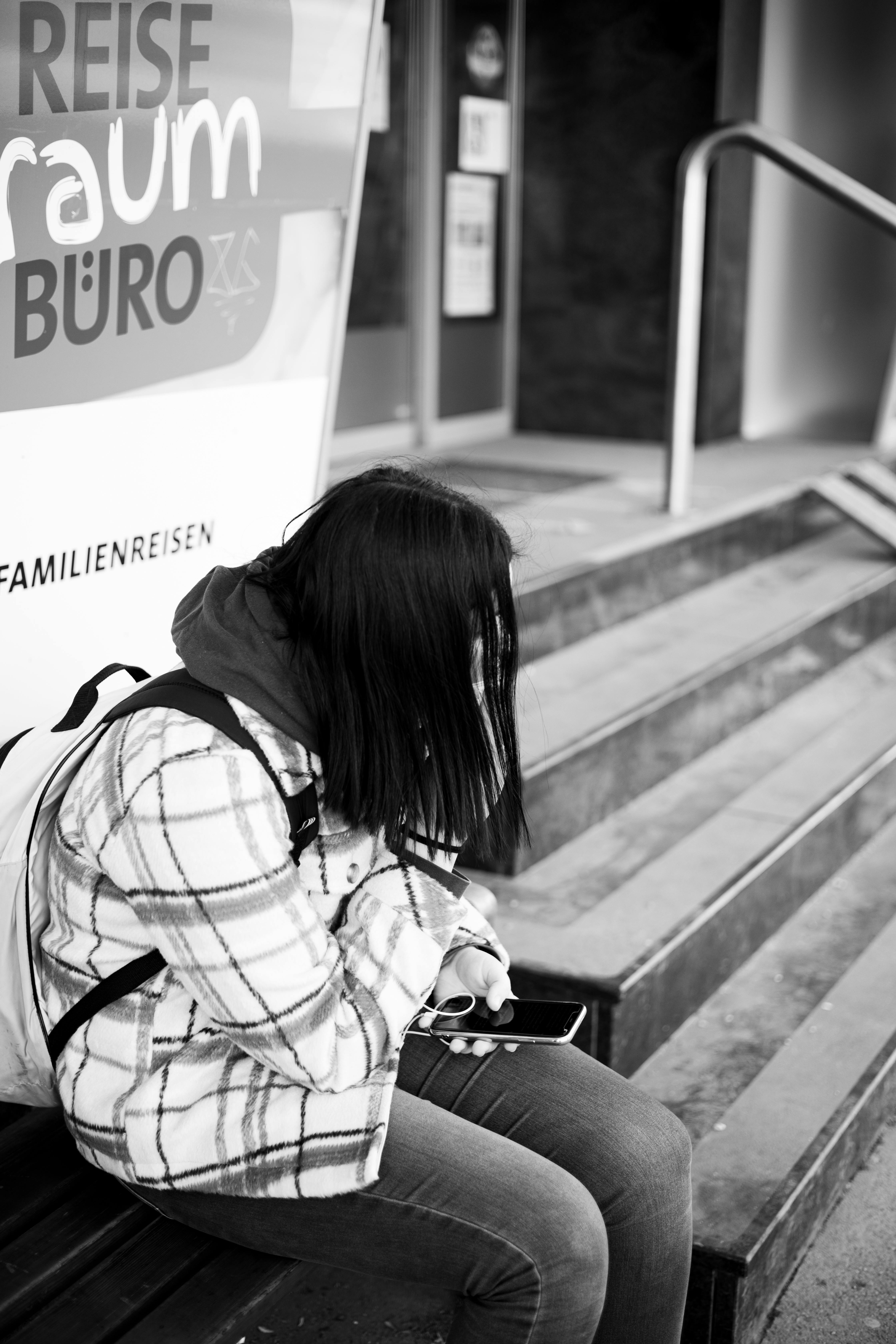 Ein Mädchen sitzt auf einer Bank und hält ihr Handy in der Hand | Quelle: Pexels