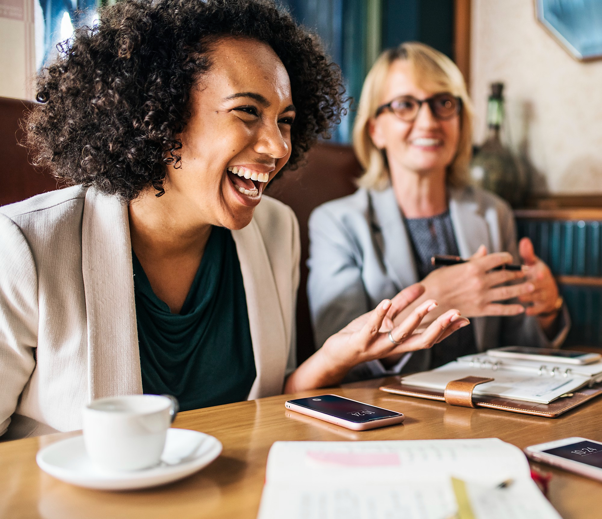 Eine jüngere Frau und eine ältere Frau lachen bei einem Kaffee-Date | Quelle: Freepik