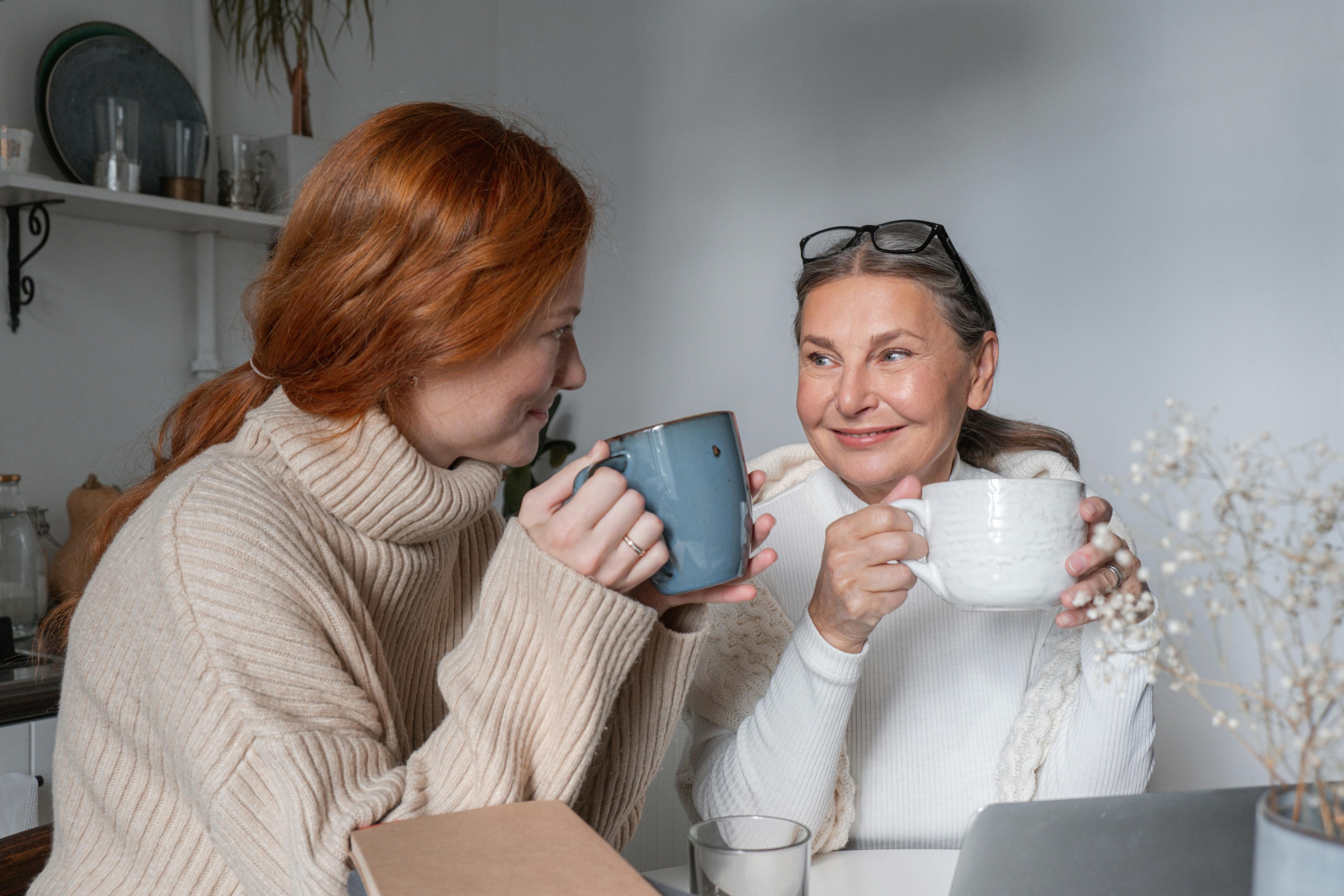 Eine ältere Frau und eine jüngere Frau lächeln, während sie zusammen ein Getränk trinken | Quelle: Pexels