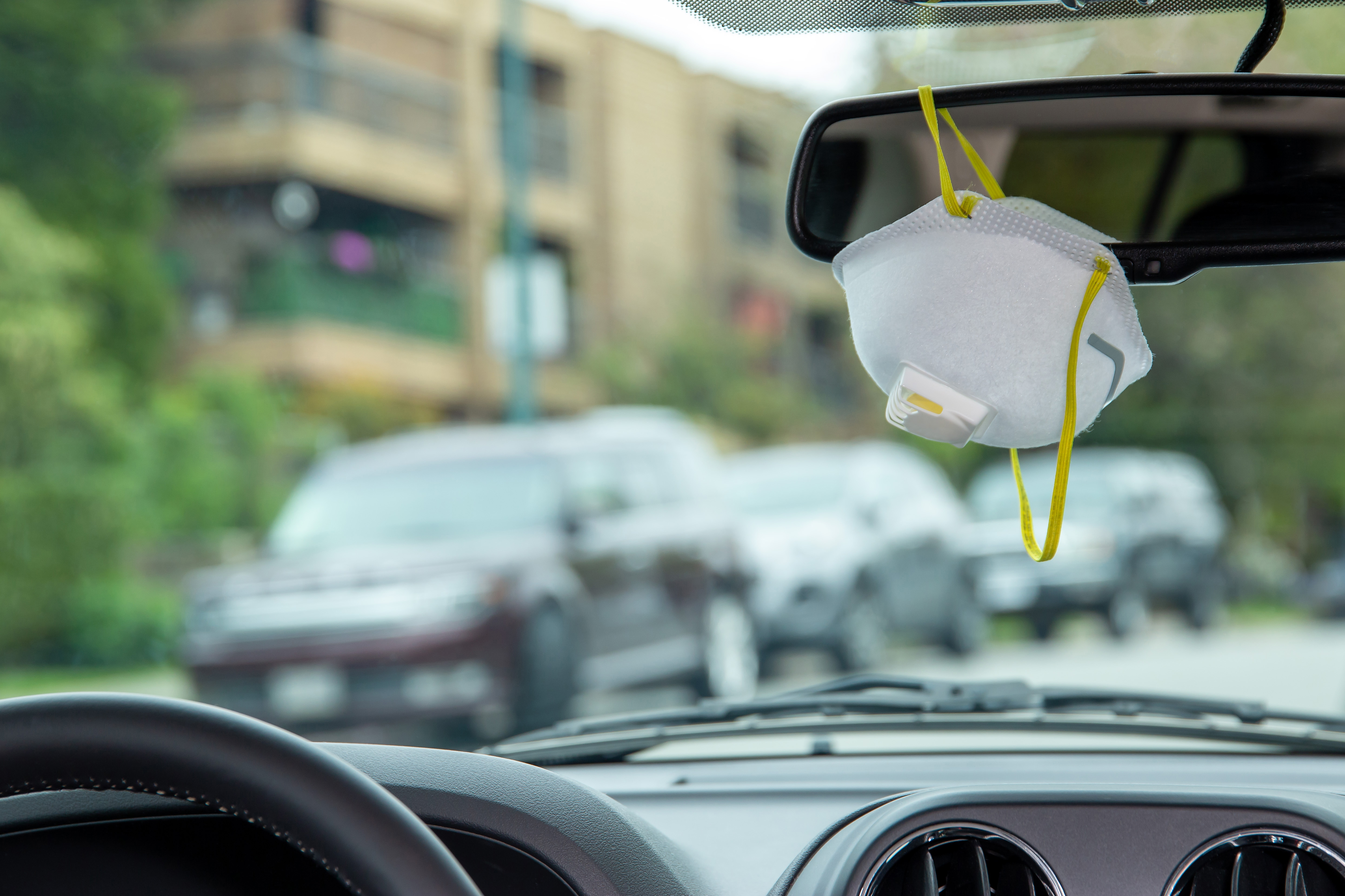 Eine Schutzmaske hängt am Rückspiegel eines Autos | Quelle: Getty Images
