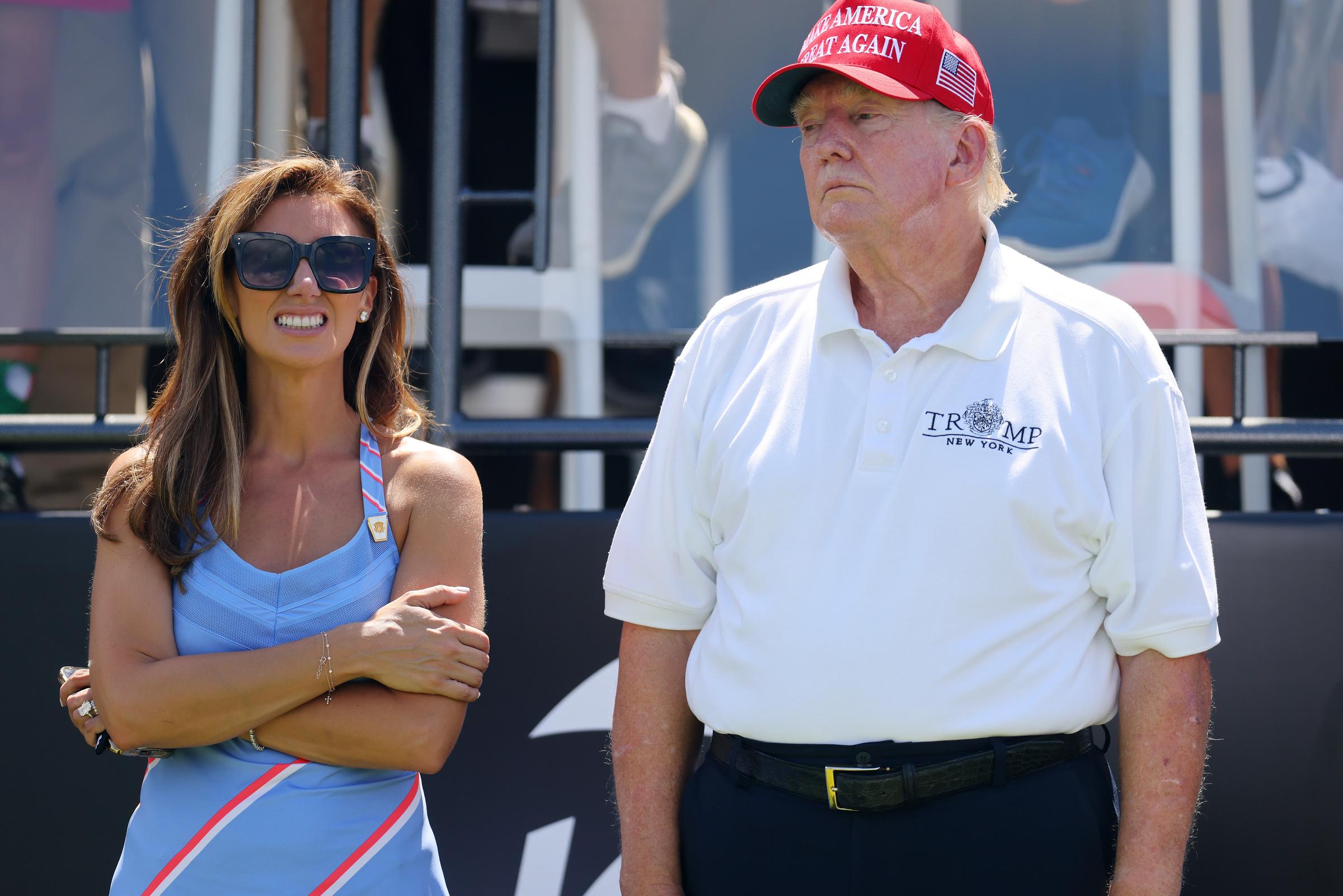 Später am selben Tag sieht man Donald Trump am ersten Abschlag neben der Anwältin Alina Habba stehen. Das Sonnenlicht macht den Farbunterschied noch deutlicher und zeigt die gerötete Haut in seinem Gesicht und die blassen Arme.