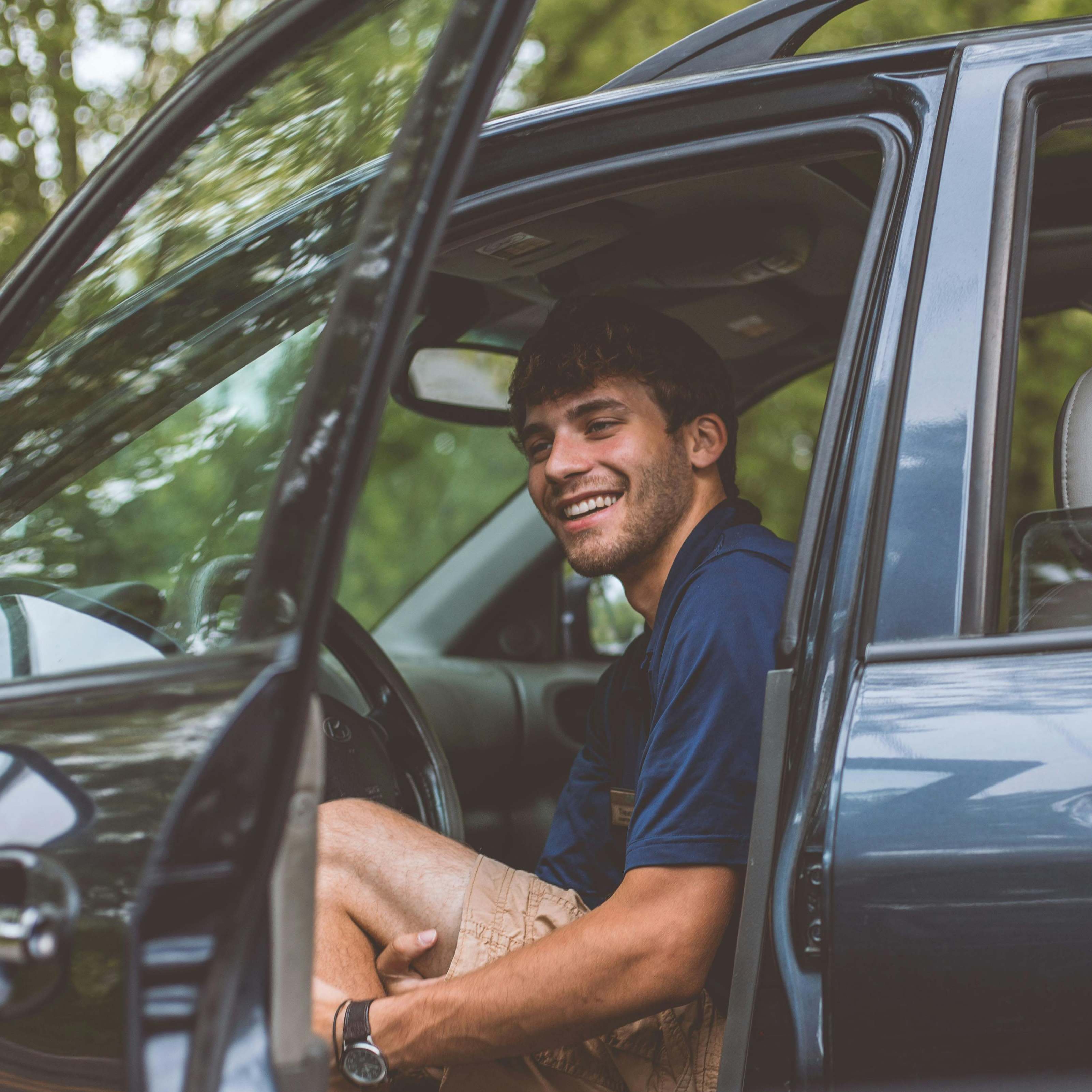 Ein Mann, der lächelnd die Fahrertür eines Autos öffnet | Quelle: Pexels