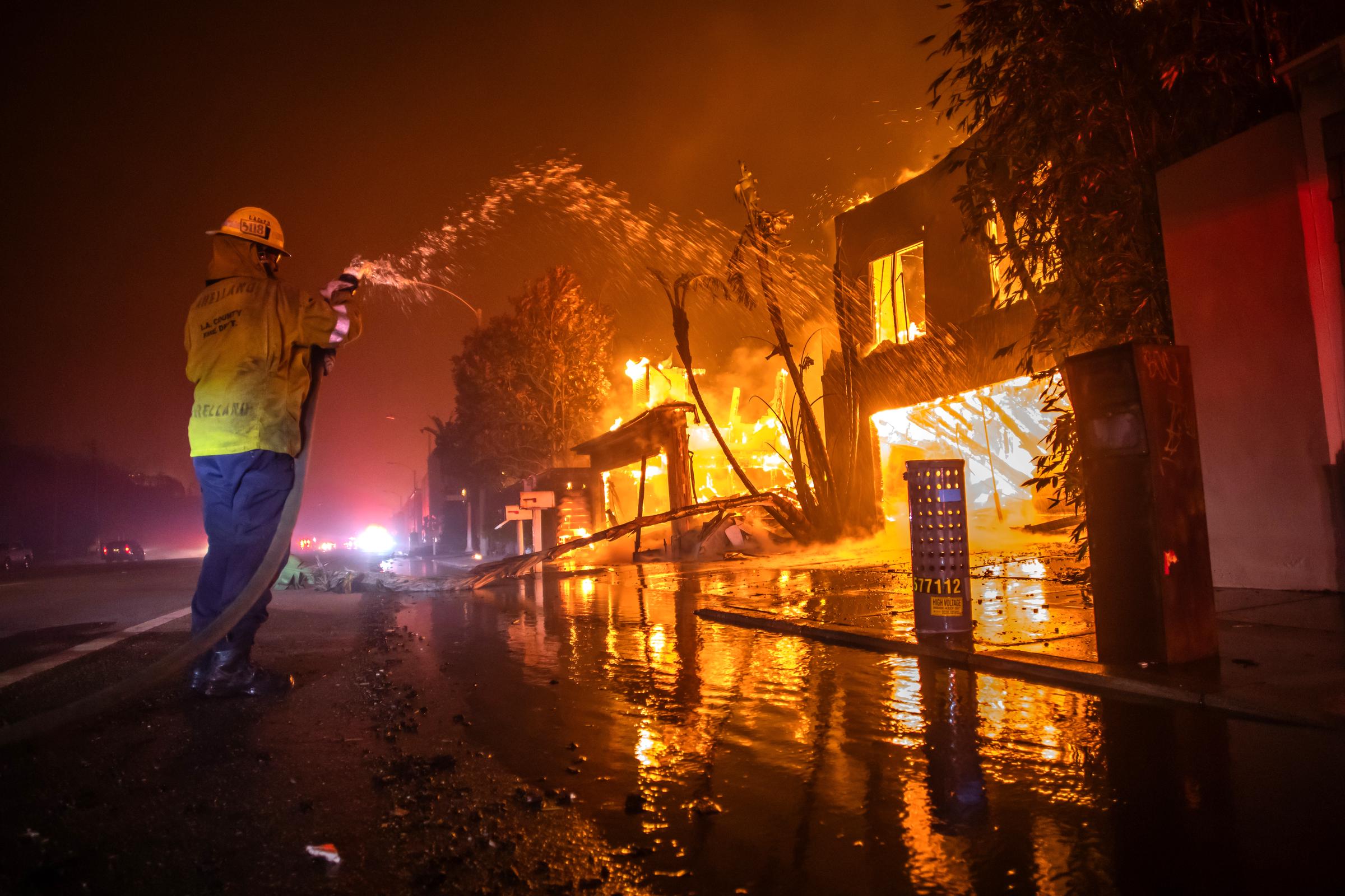 Ein Feuerwehrmann bekämpft das Palisades Fire, während es am Pacific Coast Highway in Los Angeles, Kalifornien, am 8. Januar 2025 inmitten eines starken Sturms Häuser abbrennt | Quelle: Getty Images