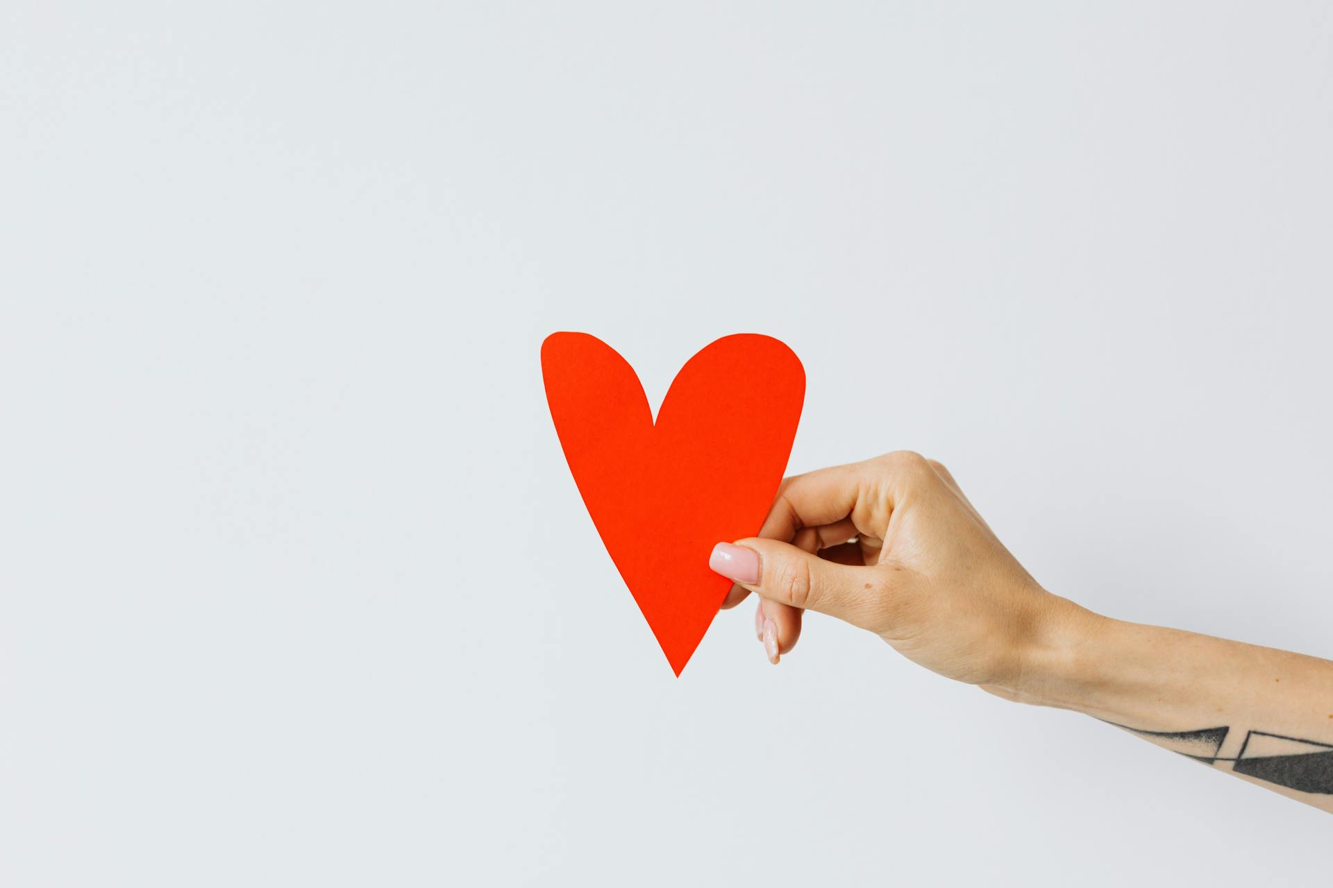 Eine Frau, die ein rotes Papierherz hält | Quelle: Pexels