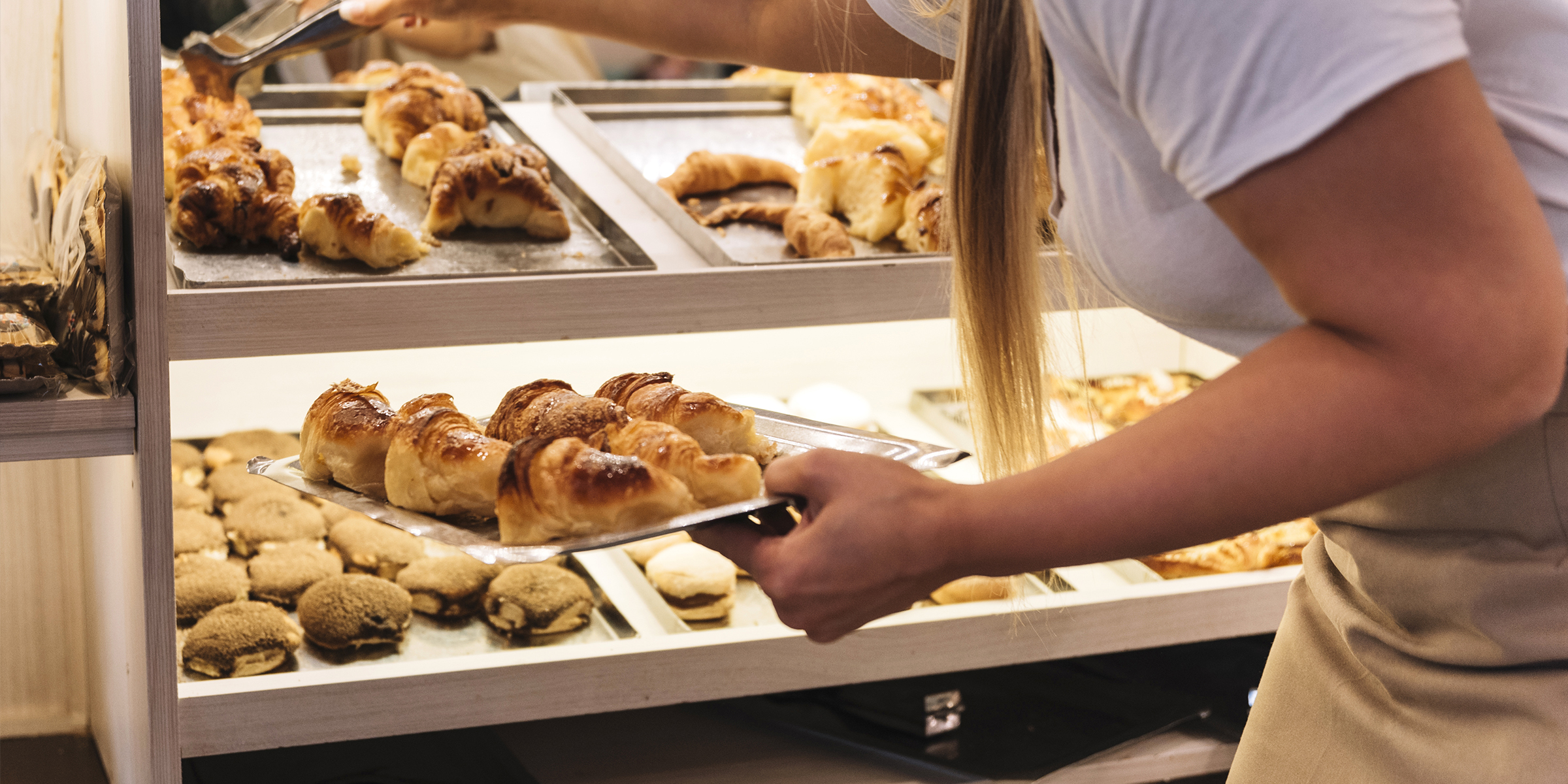 Eine Frau bestückt eine Bäckereivitrine | Quelle: Freepik