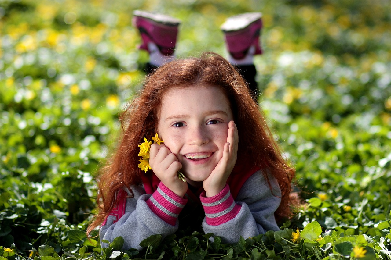 Ein lächelndes rothaariges Mädchen hält Blumen | Quelle: Pixabay
