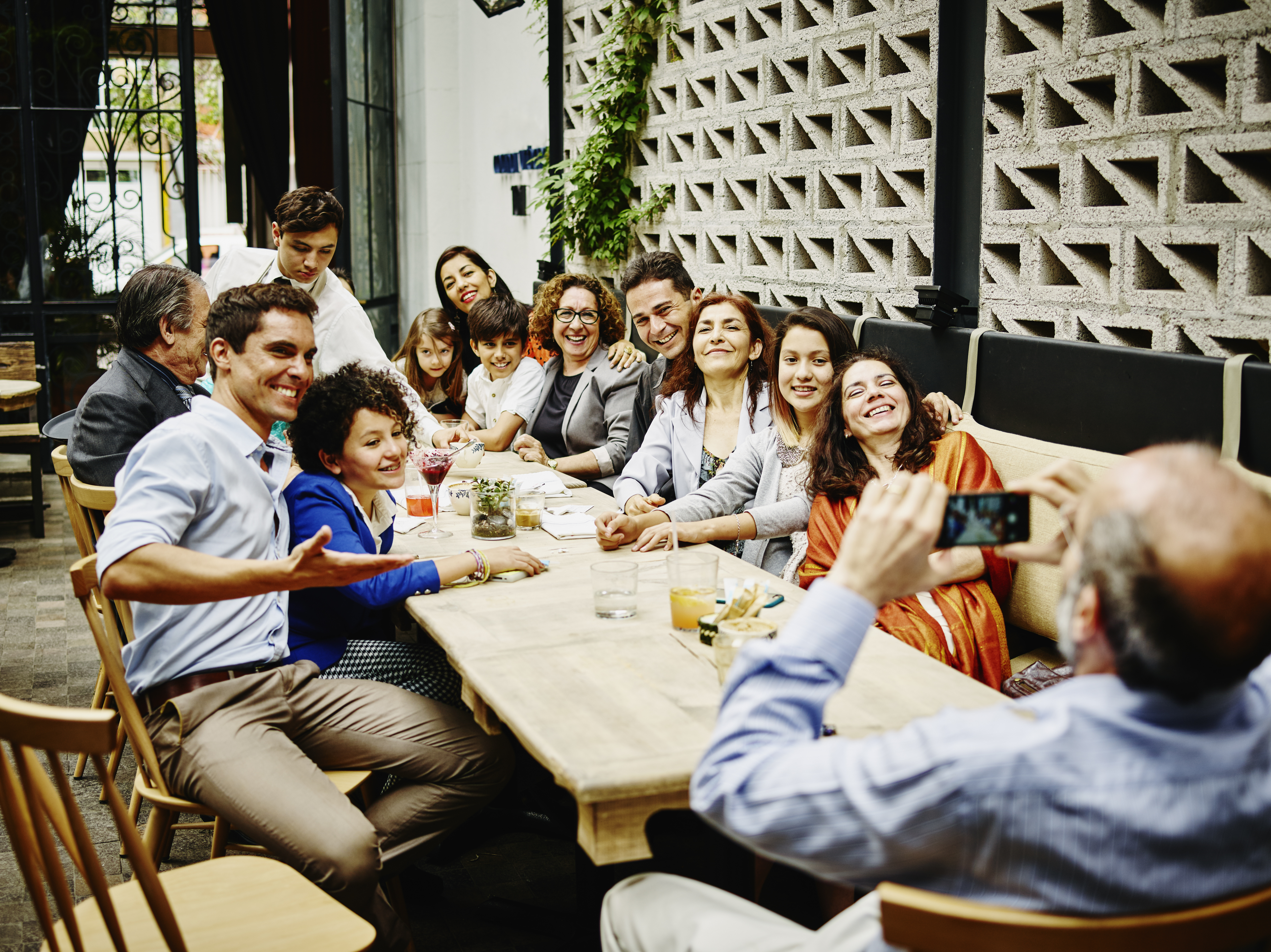 Ein Mann macht ein Familienfoto mit seinem Smartphone während einer Dinnerparty in einem Restaurant | Quelle: Getty Images
