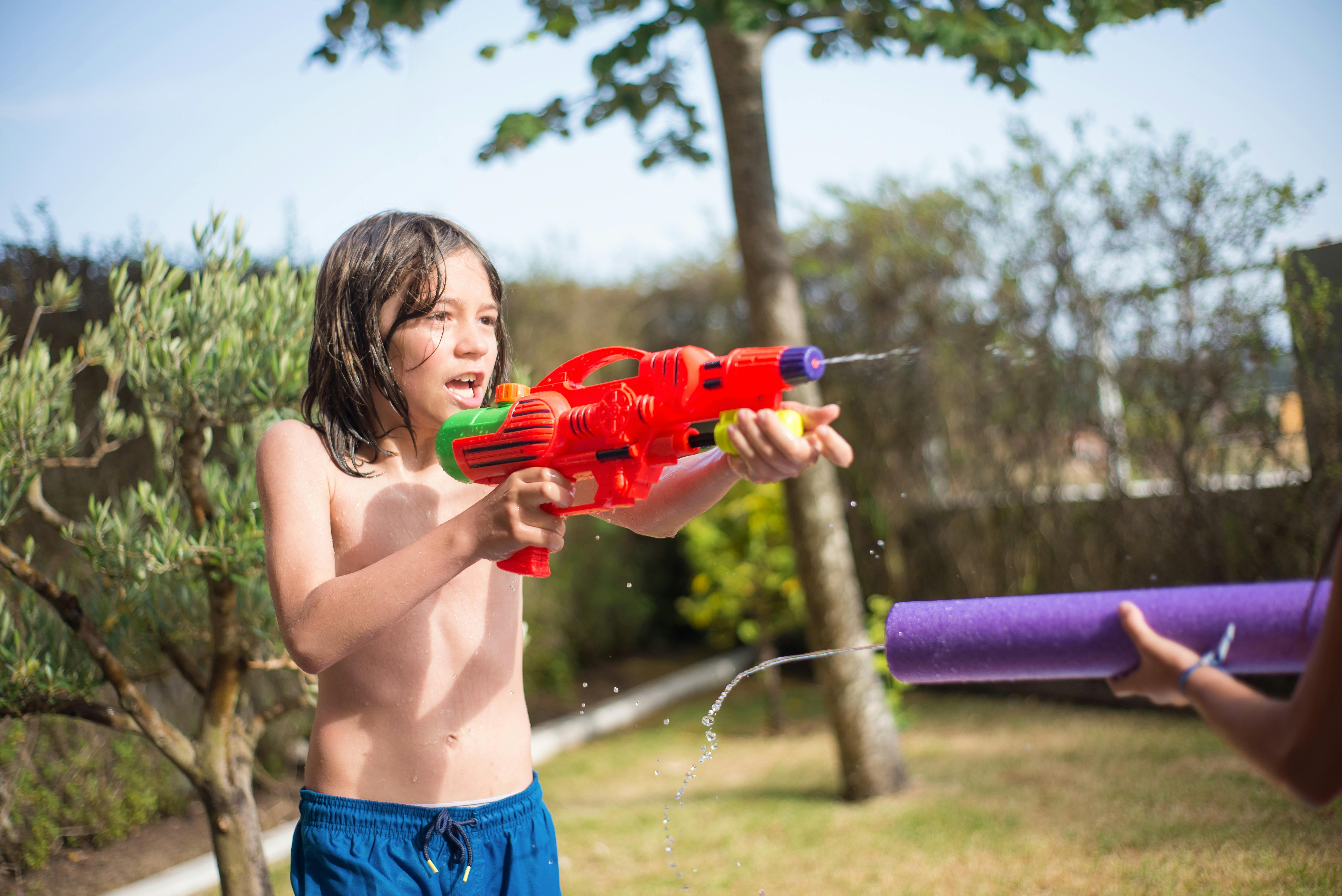 Ein Junge spielt mit einer Wasserpistole | Quelle: Pexels