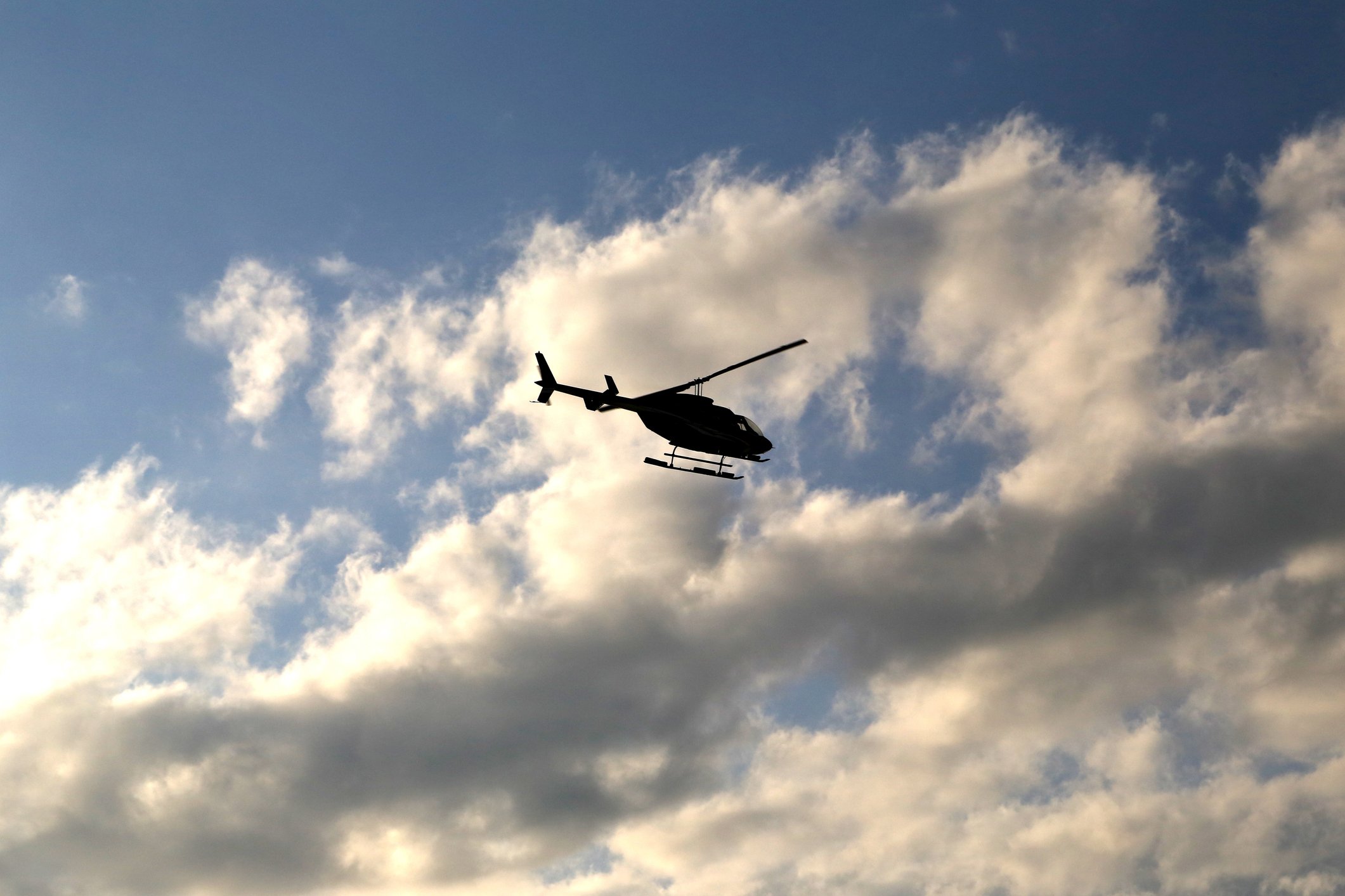 Silhouette eines Hubschraubers, der in den teilweise bewölkten Himmel fliegt I Quelle: Getty Images