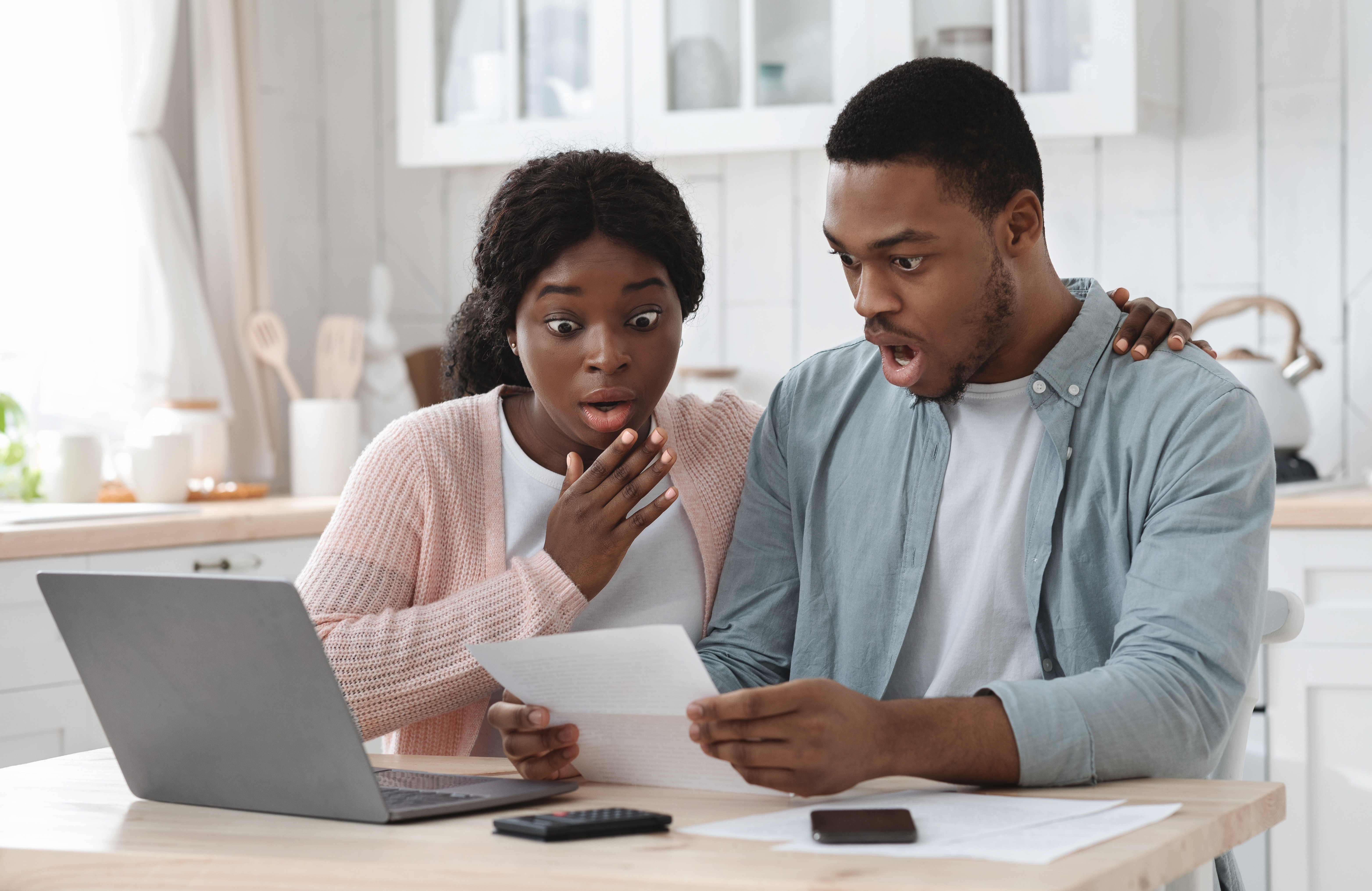 Schockiertes schwarzes Paar in der Küche, das finanzielle Probleme hat und das Familienbudget berechnet | Quelle: Getty Images