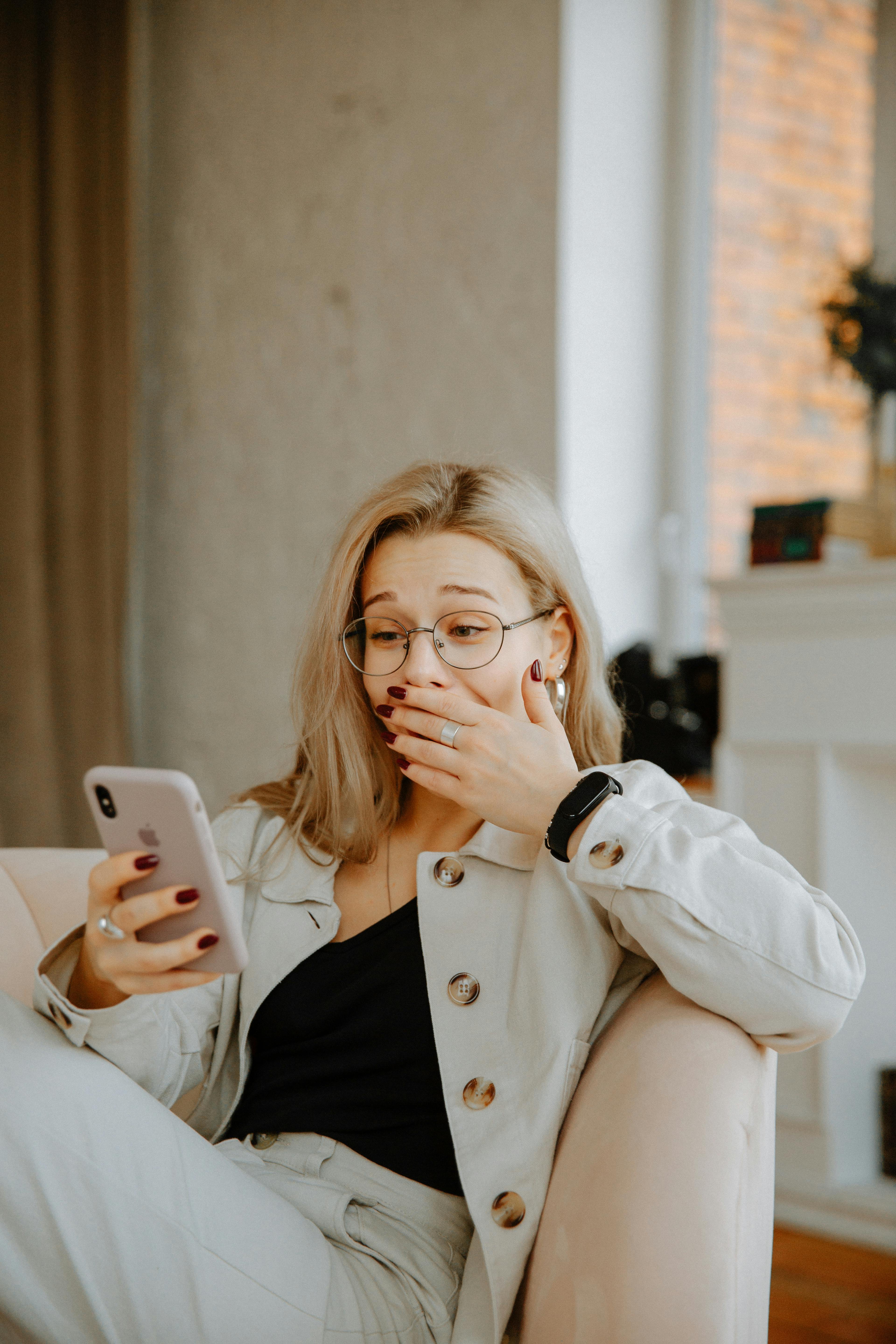 Eine Frau, die ihr Gesicht bedeckt, während sie auf ihr Telefon schaut | Quelle: Pexels