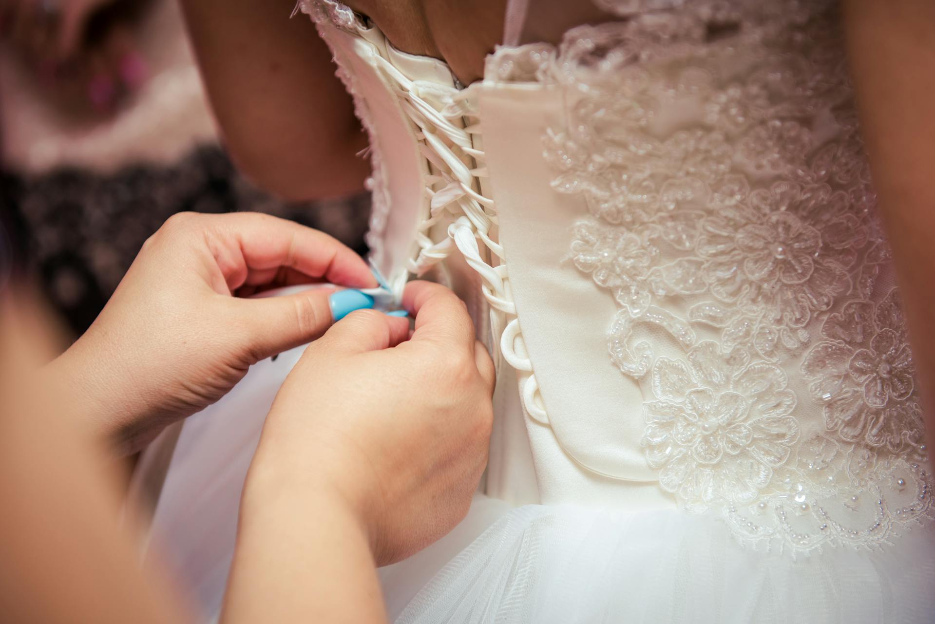 Nahaufnahme einer Frau, die ein Hochzeitskleid repariert | Quelle: Pexels