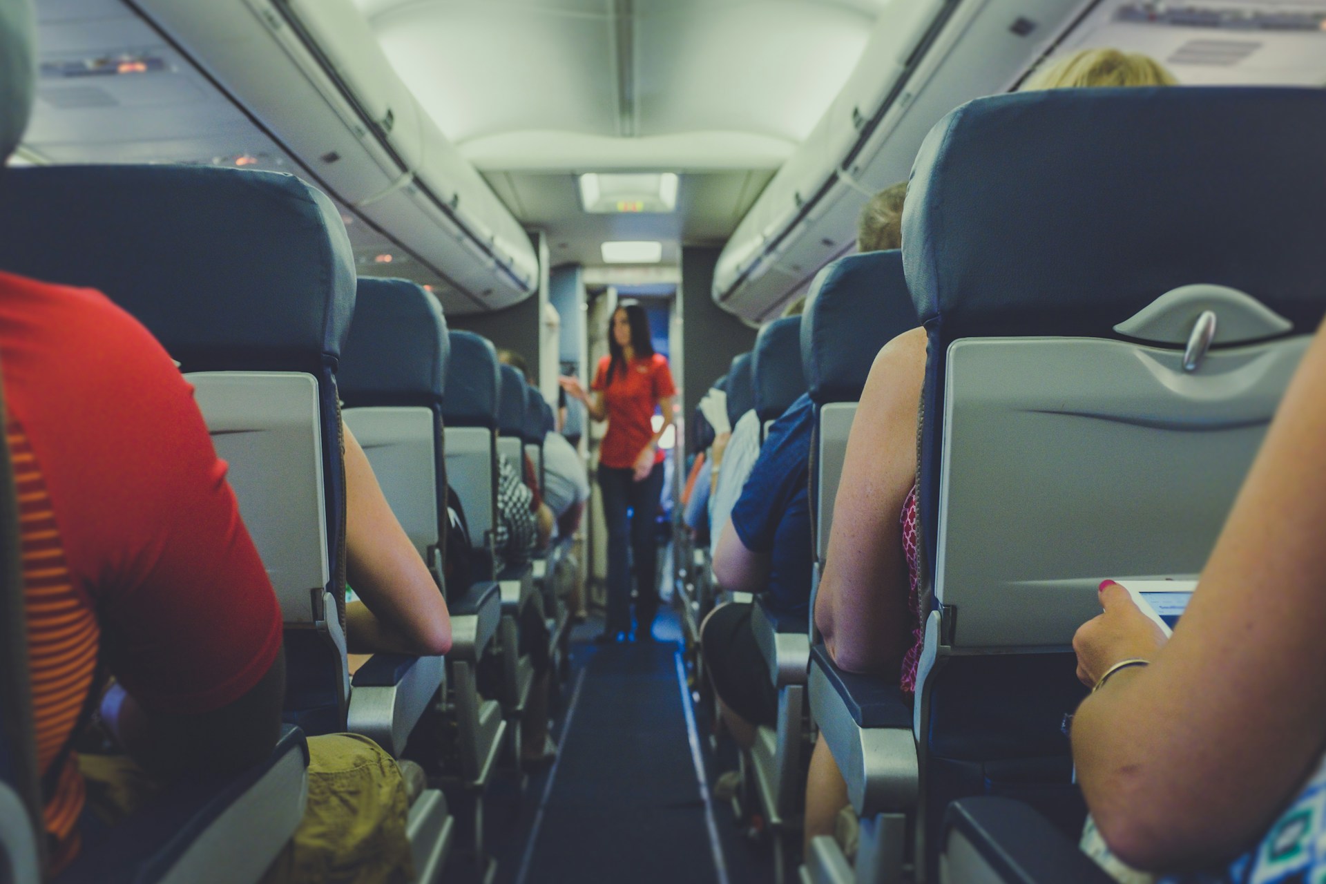 Eine Flugbegleiterin, die sich um die Probleme der Passagiere im Economy-Gang kümmert | Quelle: Unsplash