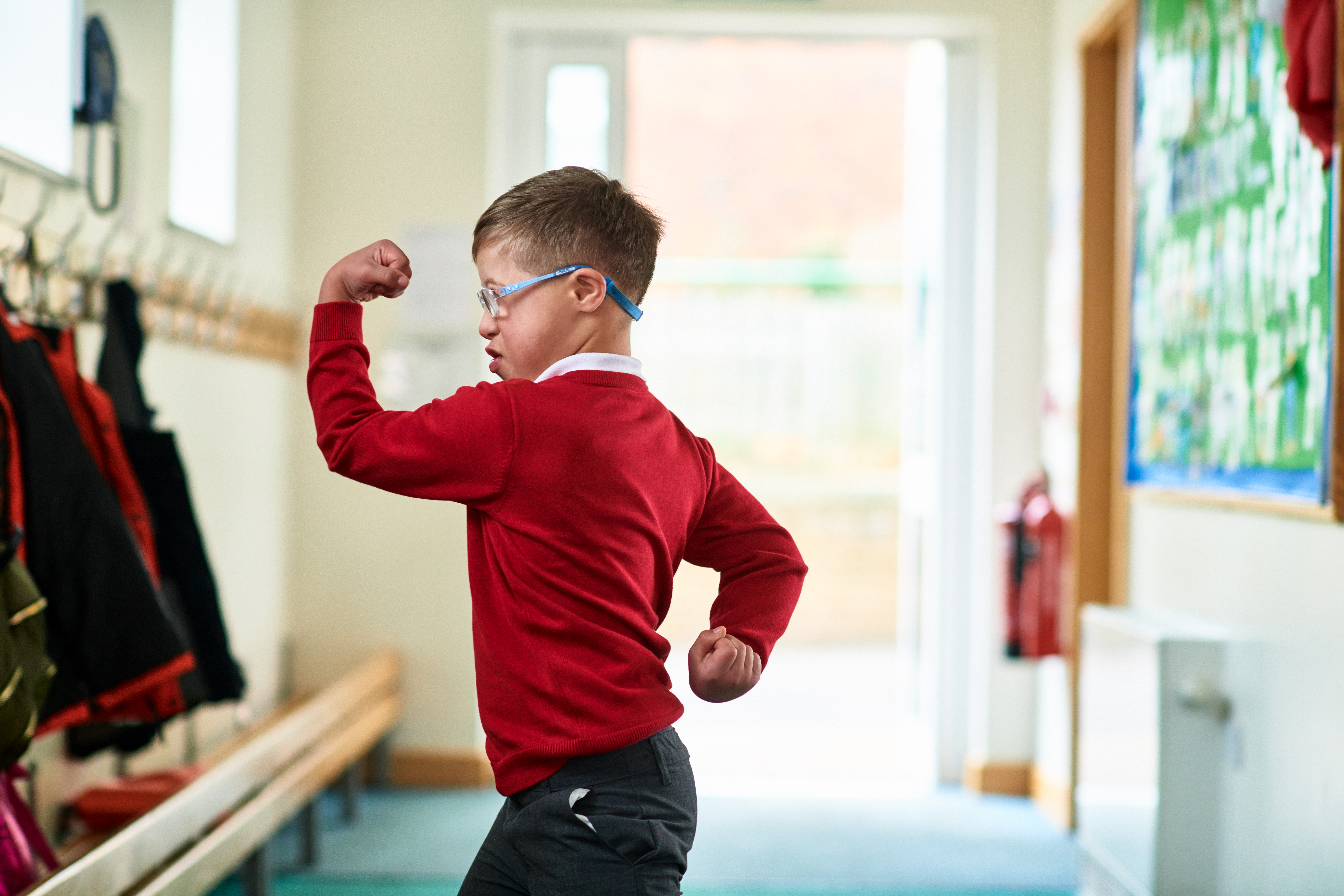 Junge mit Down-Syndrom beim Muskeltraining im Schulkorridor | Quelle: Getty Images