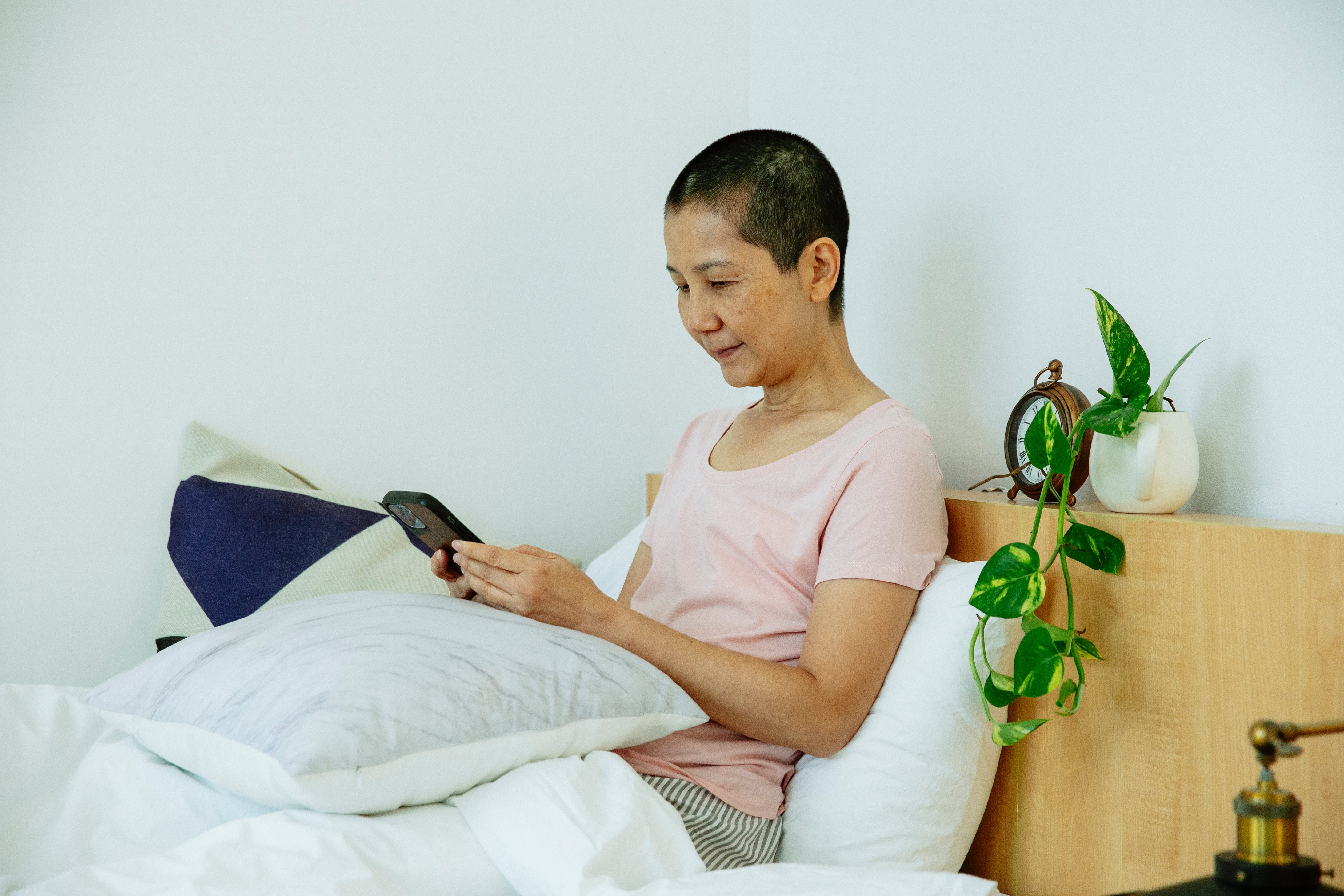Eine Frau, die auf dem Bett ein Smartphone benutzt┃Quelle: Pexels