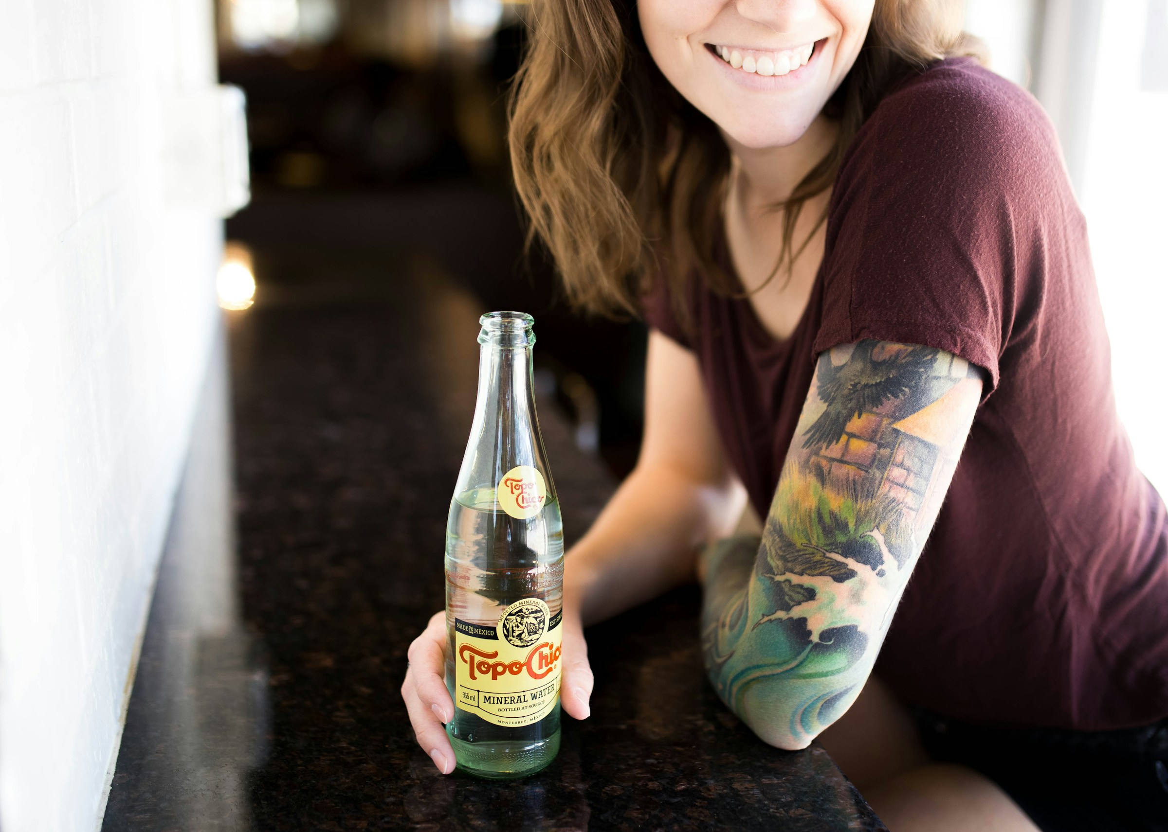 Eine Frau mit einem Tattoo, die eine Flasche hält | Quelle: Unsplash