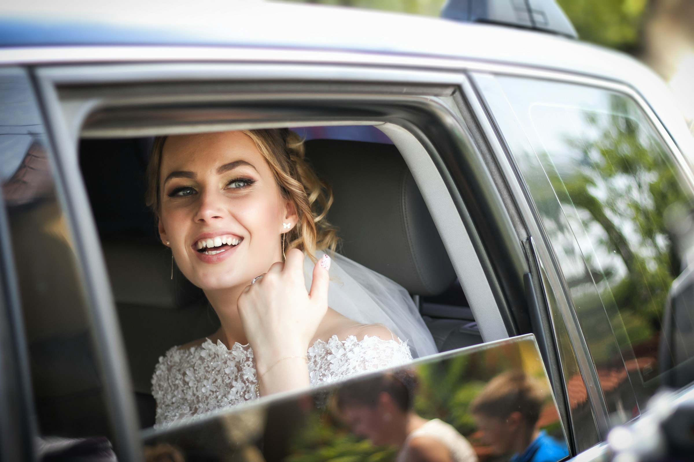 Eine Braut in einem Auto, die nach draußen schaut und lächelt | Quelle: Unsplash