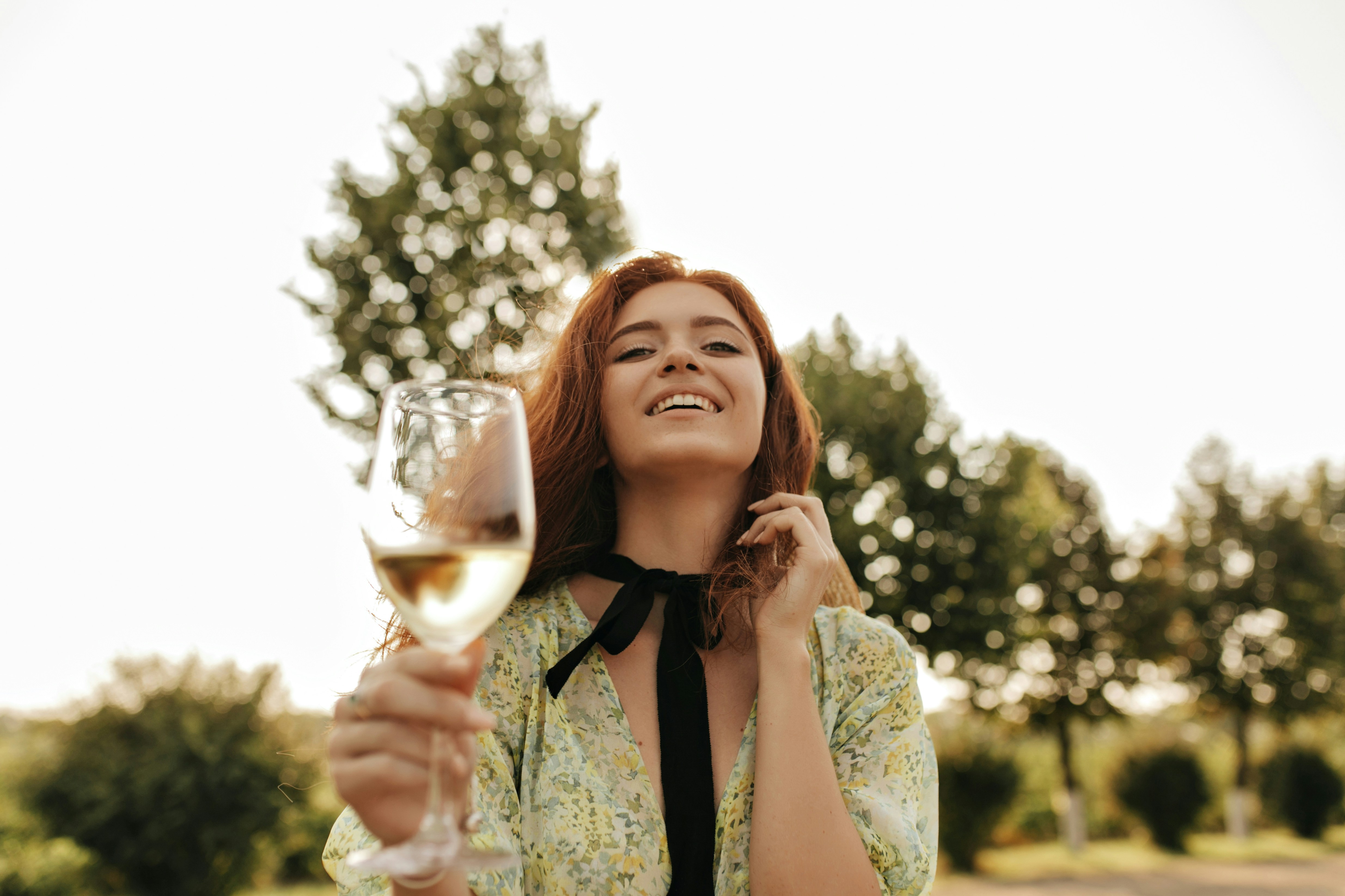Eine Frau lacht, während sie ein Glas Wein hält | Quelle: Unsplash