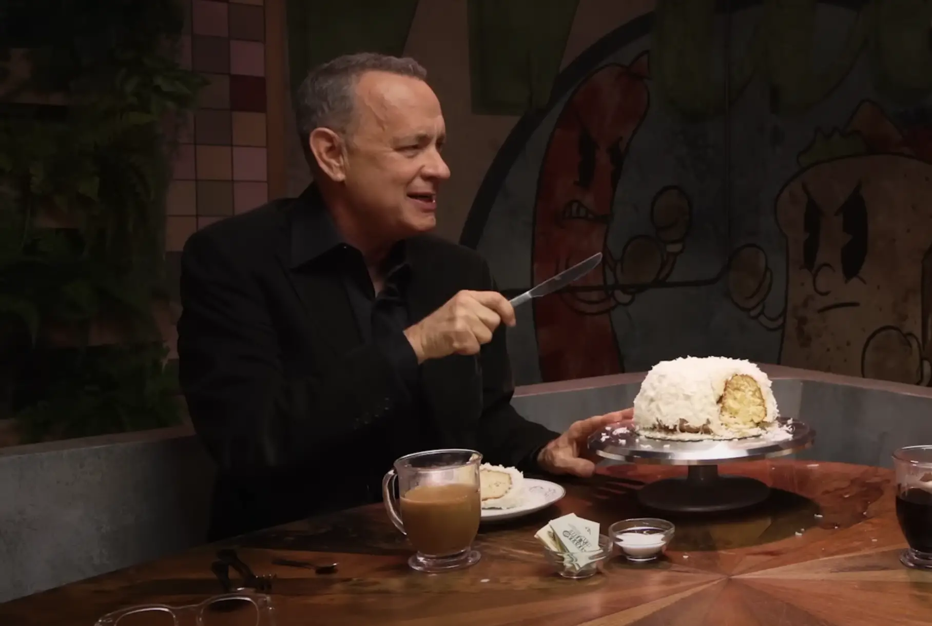 Tom Hanks zeigt die Bunt-Torte von Doan's Bakery, die er als Weihnachtsgeschenk von Tom Cruise erhält. Die Torte wurde auf Mythical Kitchen am 19. Januar 2023 gezeigt | Quelle: YouTube/Mythical Kitchen