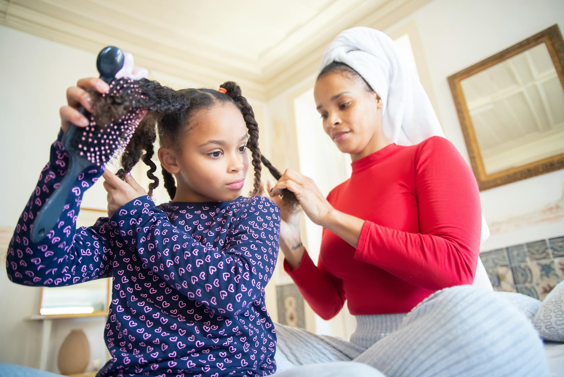 Eine Mutter flechtet die Haare ihrer Tochter | Quelle: Pexels
