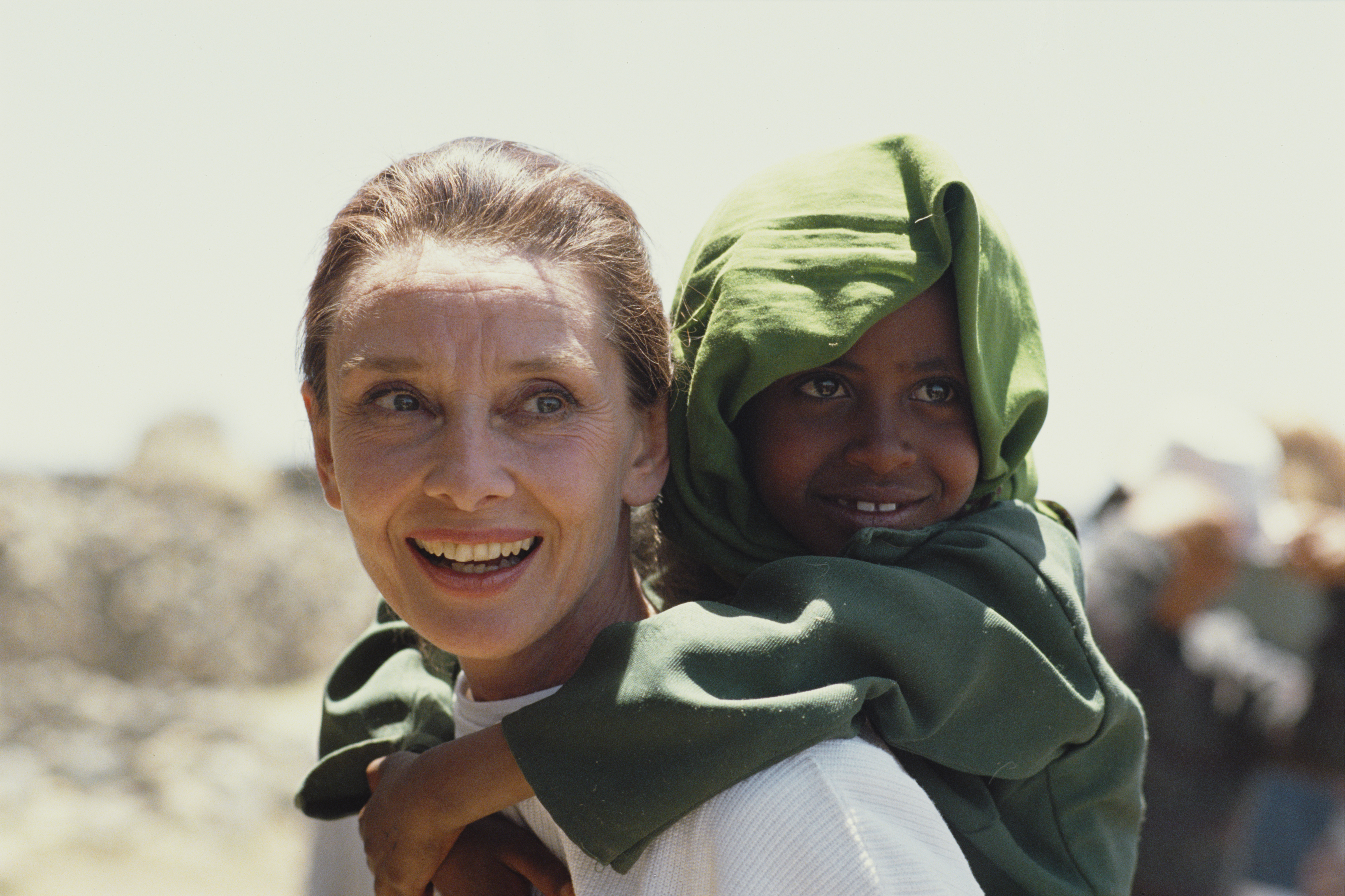 Audrey Hepburn trägt ein äthiopisches Mädchen auf ihrem Rücken, als sie im März 1988 ihren ersten Einsatz für UNICEF in Äthiopien absolviert. | Quelle: Getty Images