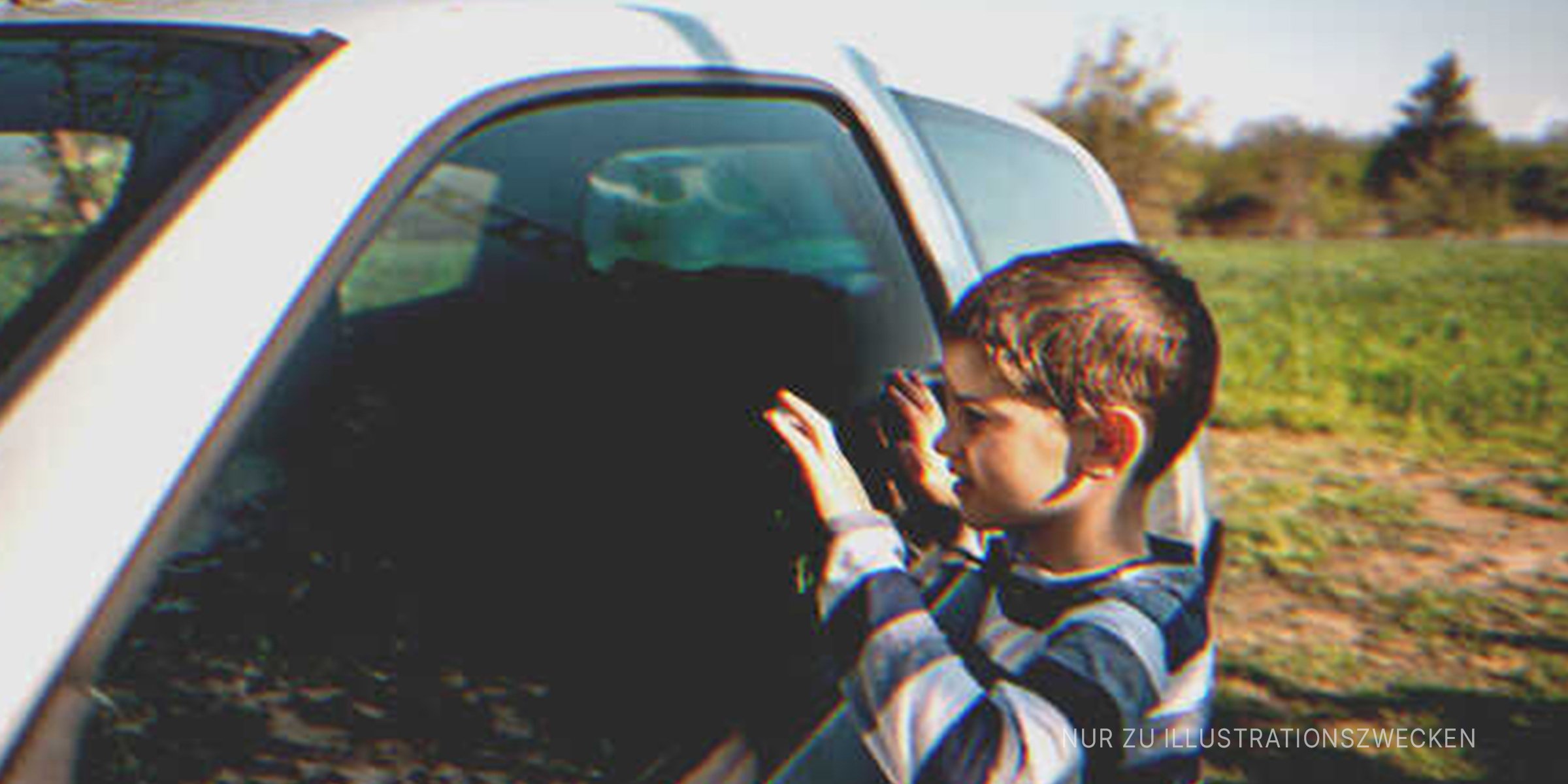 Kleiner Junge späht in ein Auto | Quelle: Getty Images