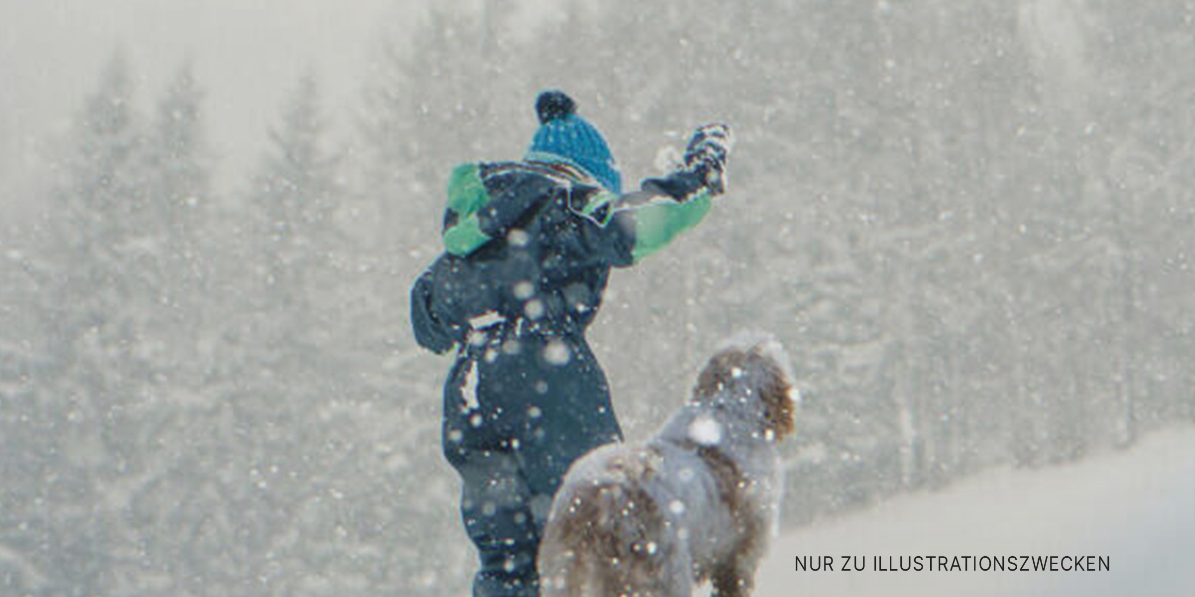 Ein Junge und ein Hund spielen im Schnee. | Quelle: Getty Images